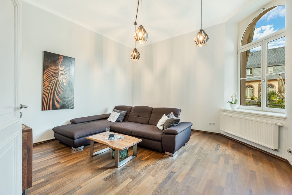 Helles Wohnzimmer mit braunem Ecksofa, Couchtisch, Zebrabild und großem Fenster.