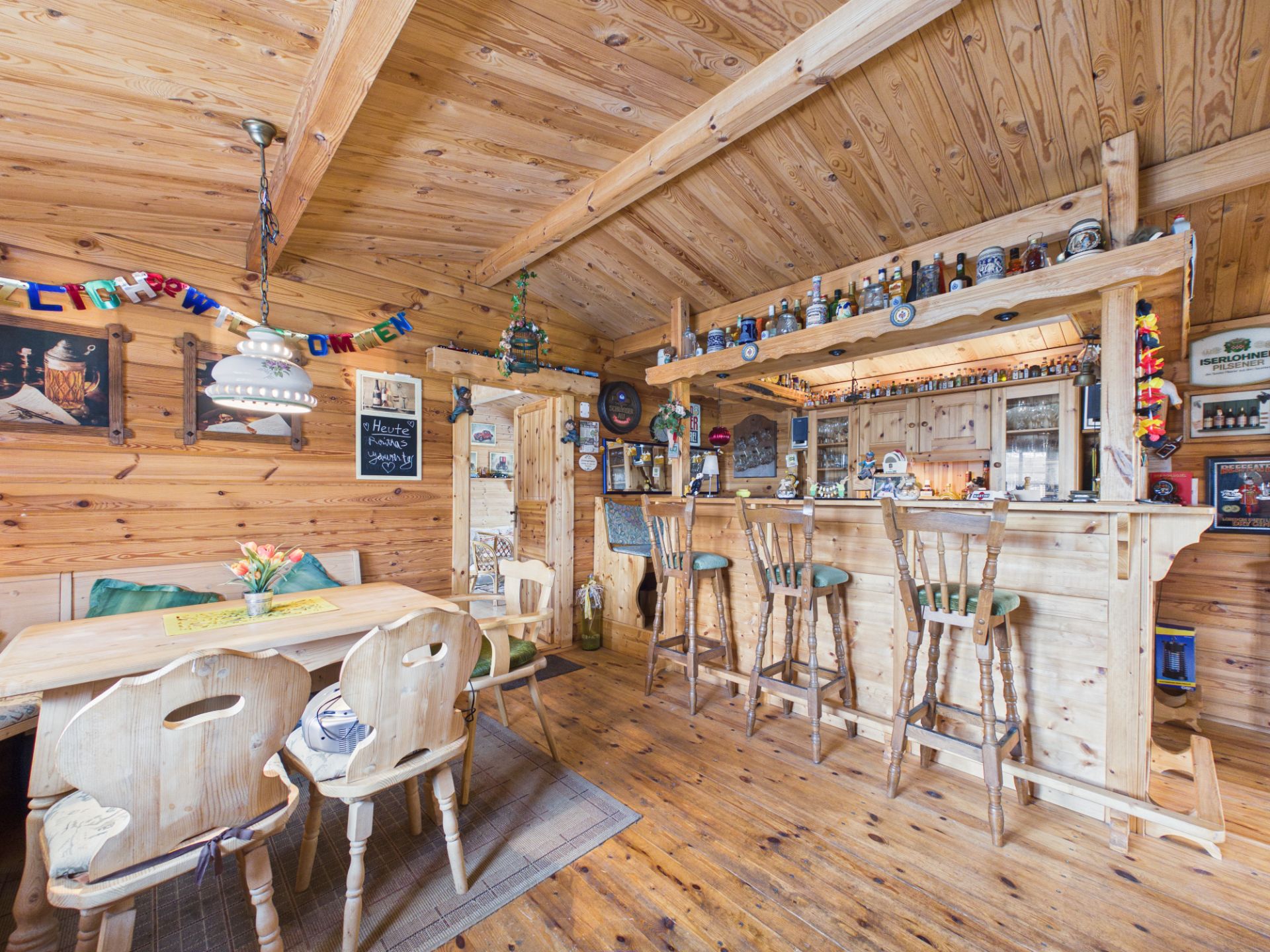 Gemütliches Wohnzimmer mit Holztäfelung, Bartresen und Esstisch mit Stühlen.