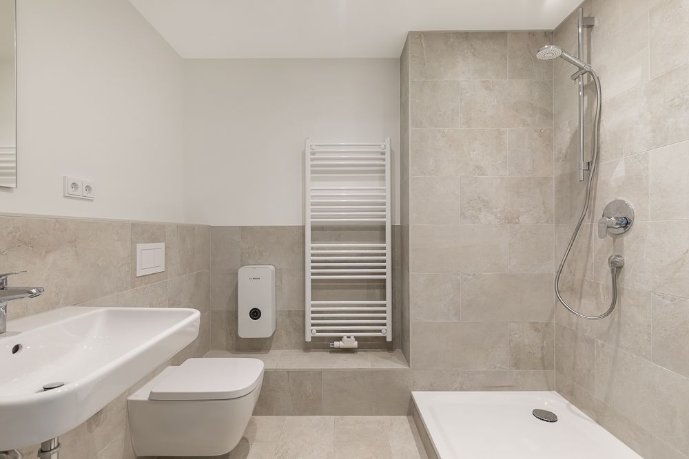 Modernes Badezimmer mit Dusche, Waschbecken, WC und Handtuchheizung.