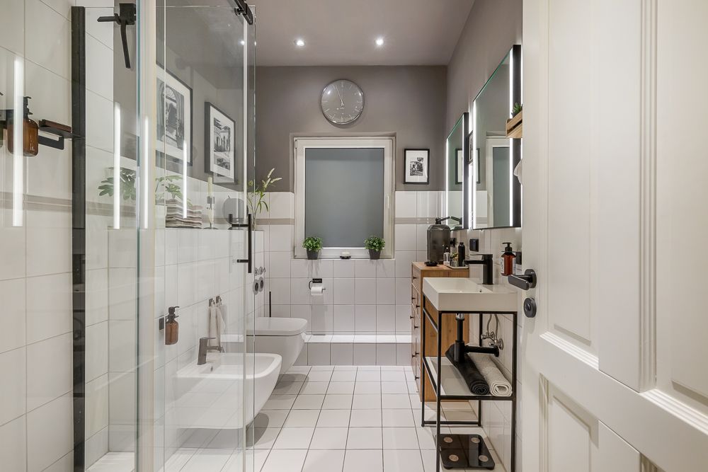 Modernes Badezimmer mit Dusche, Toilette, Bidet, Waschbecken und Wanddekorationen.