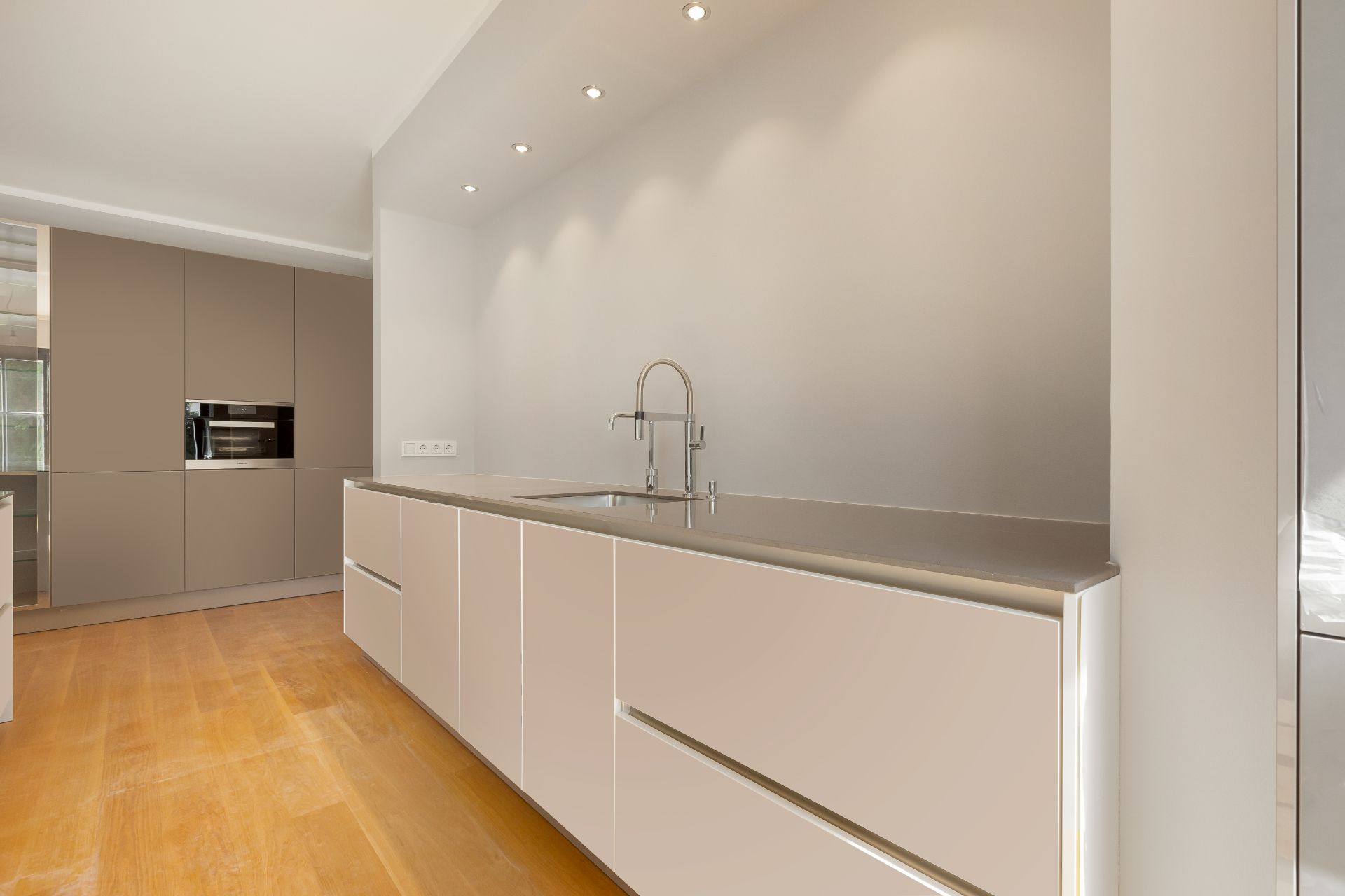 Moderne, helle Einbauküche mit Holzfußboden und Einbauschränken.