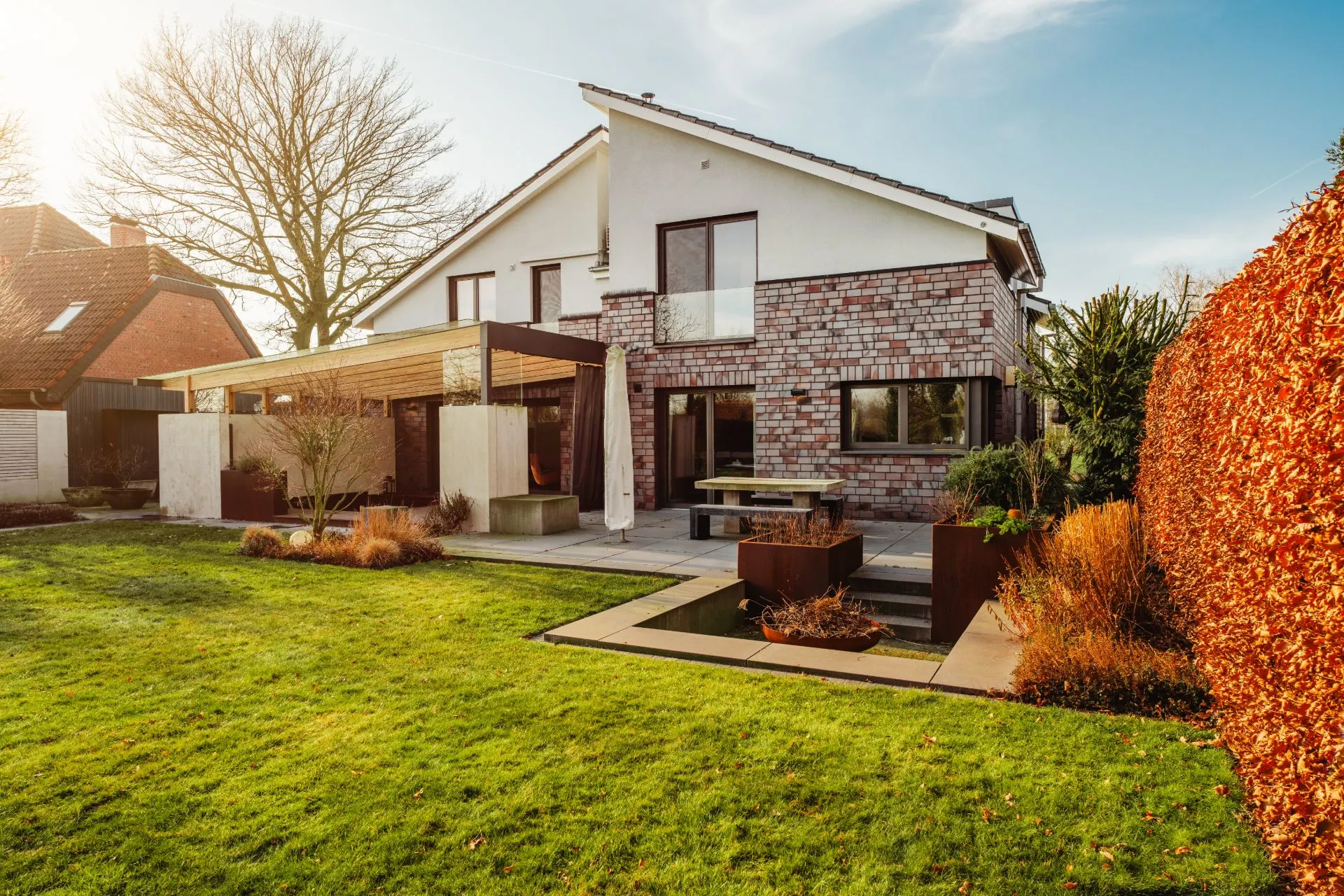Modernes Wohnhaus mit Garten, Terrasse und gepflegtem Rasen im Vordergrund.