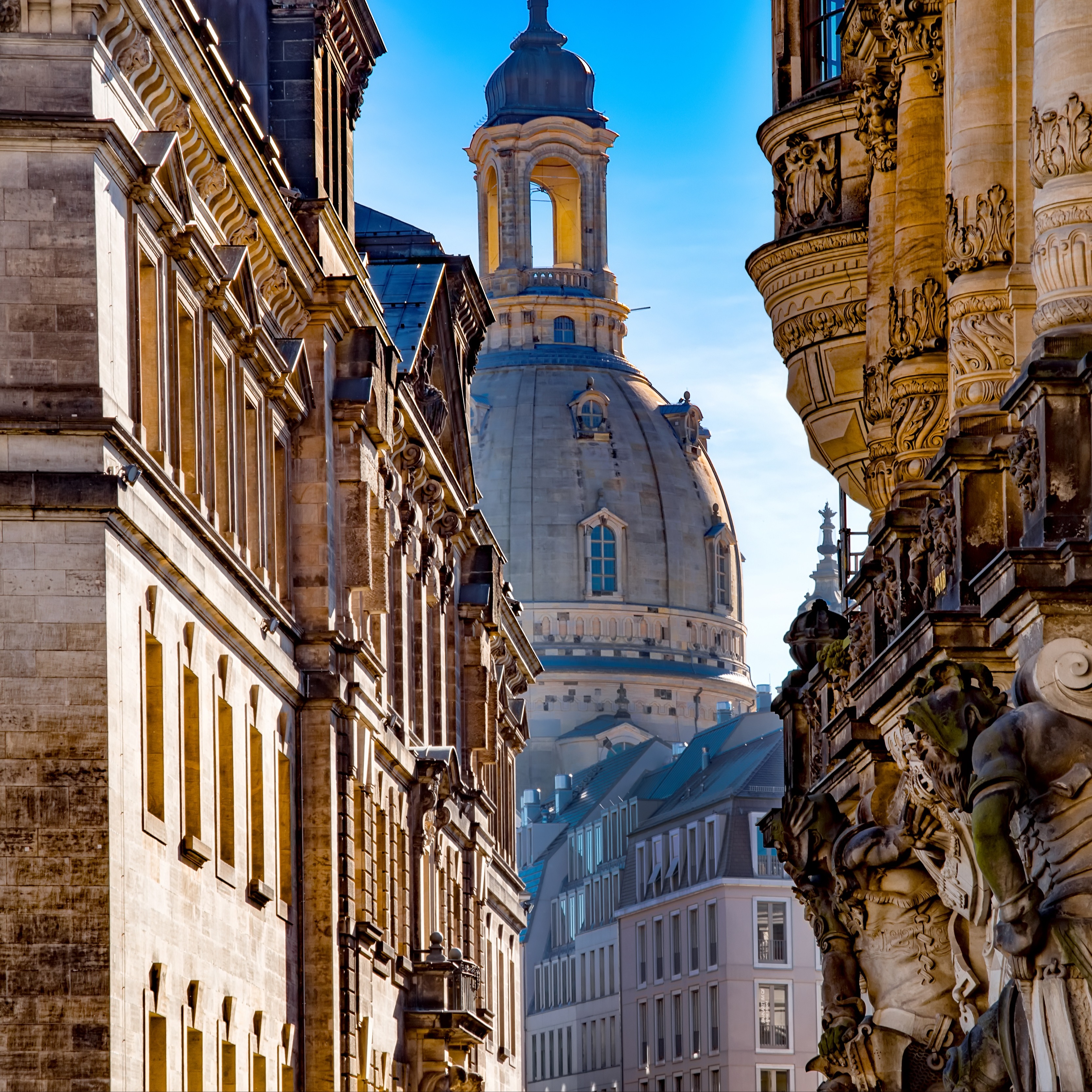 Blick zwischen historischen Wohngebäuden auf eine große Kuppel im Hintergrund.