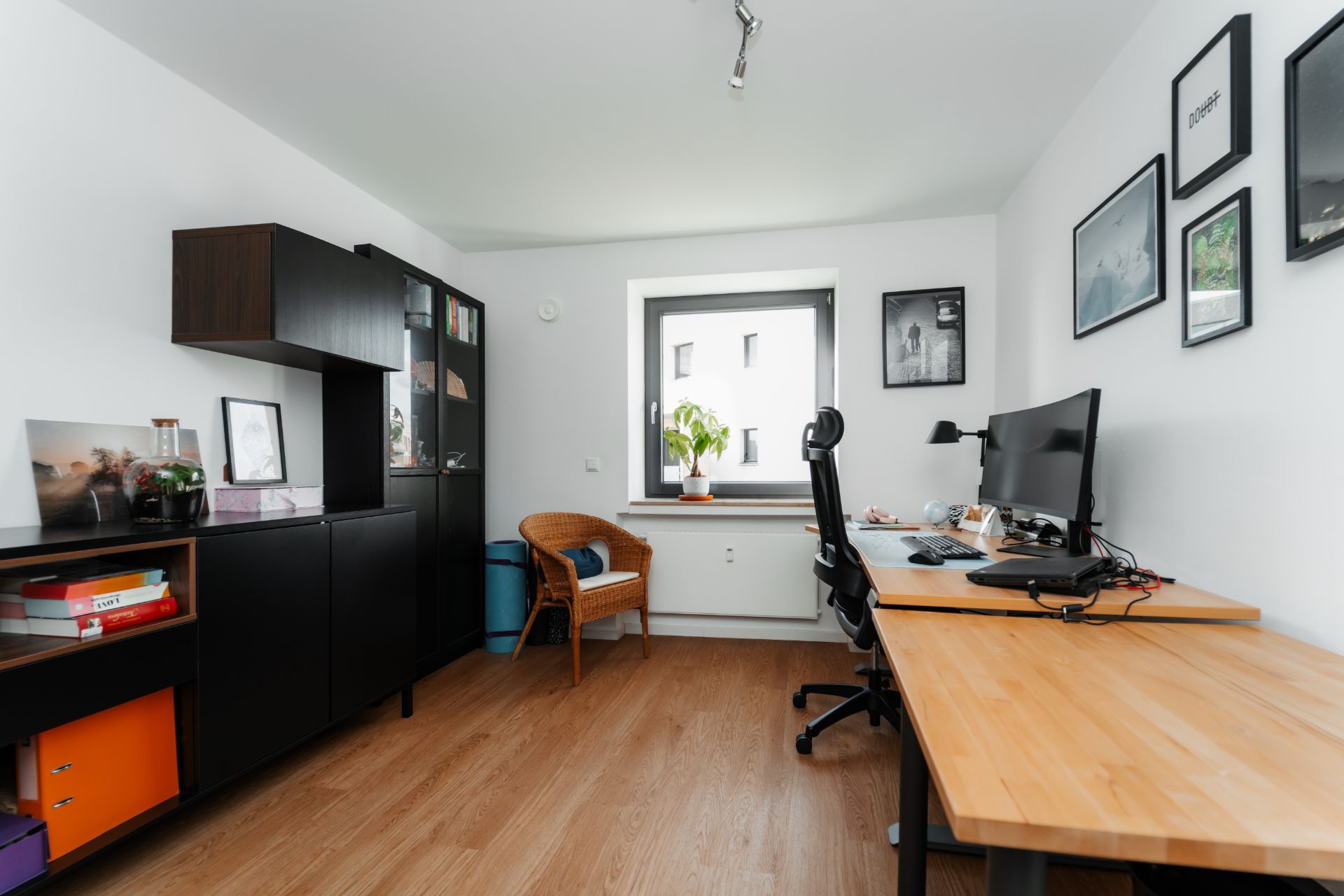 Modernes Arbeitszimmer mit Holzschreibtisch, Stuhl, Regal und großem Fenster.