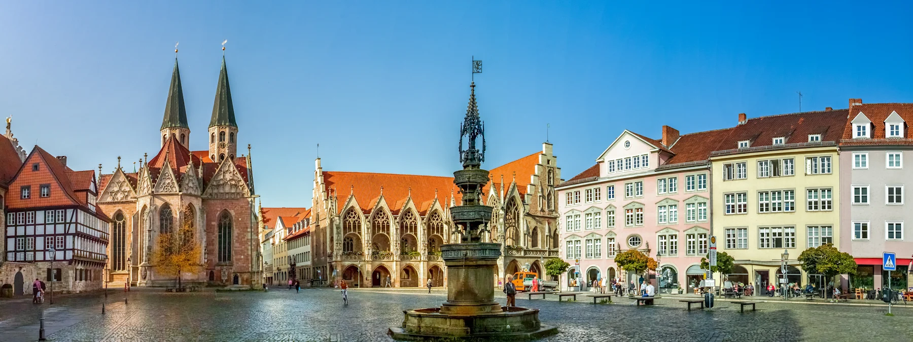 Historischer Platz mit Brunnen, Kirche und umliegenden Gebäuden bei klarem Himmel.