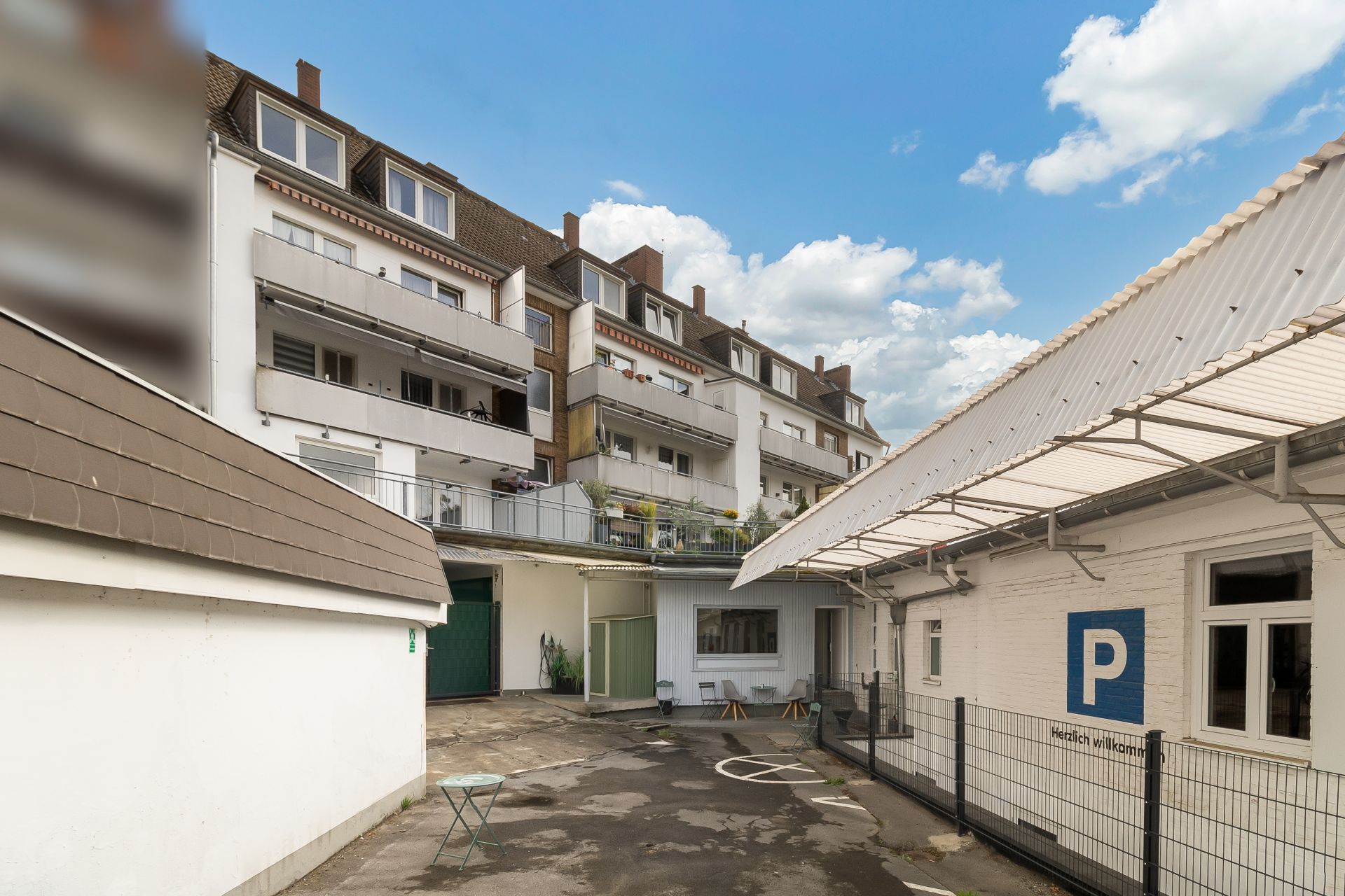 Innenhof mit Parkplätzen, Mehrfamilienhaus und angrenzendem Gebäude bei Tageslicht.