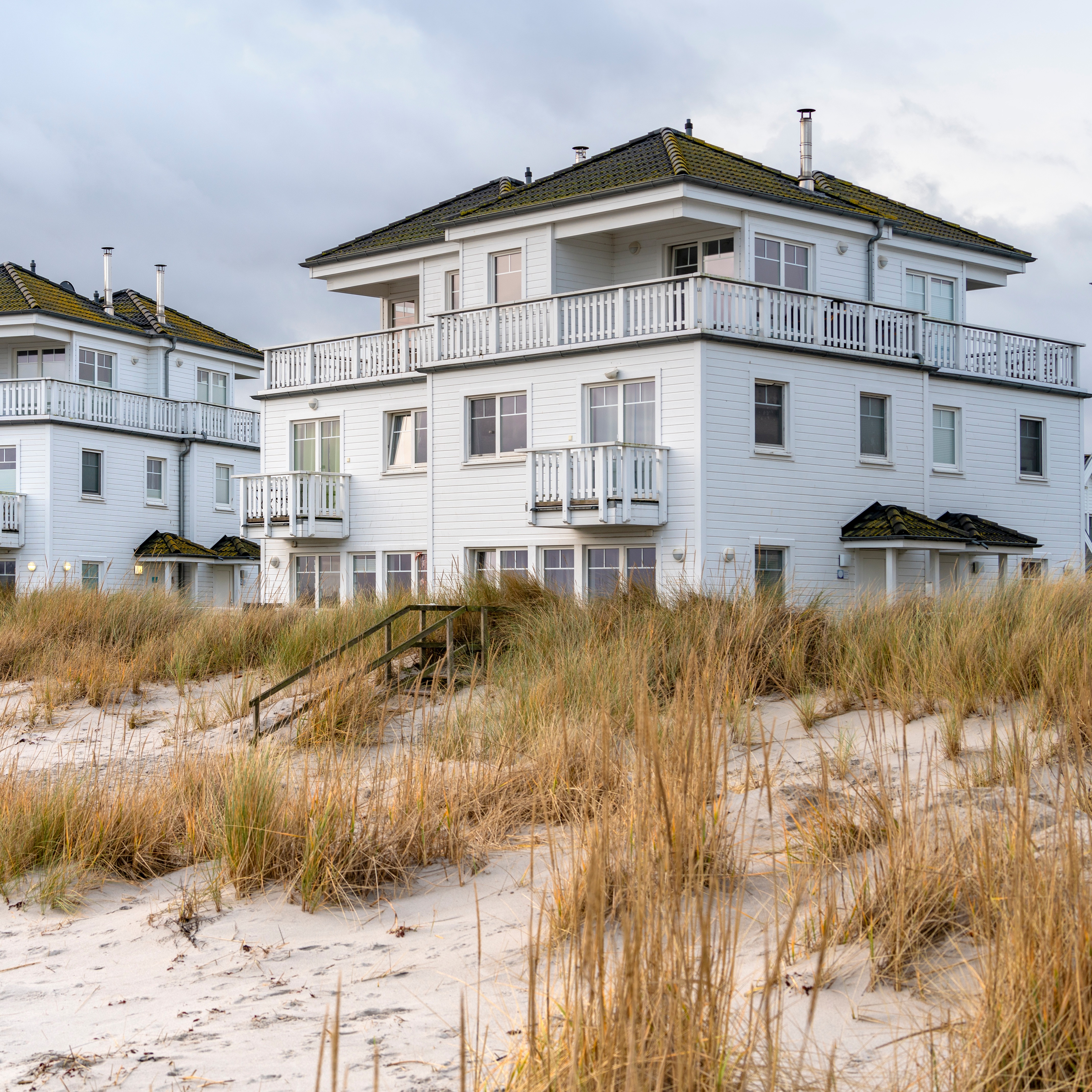 Reihe moderner, weißer Wohnhäuser mit schwarzen Dächern und Außentreppen.