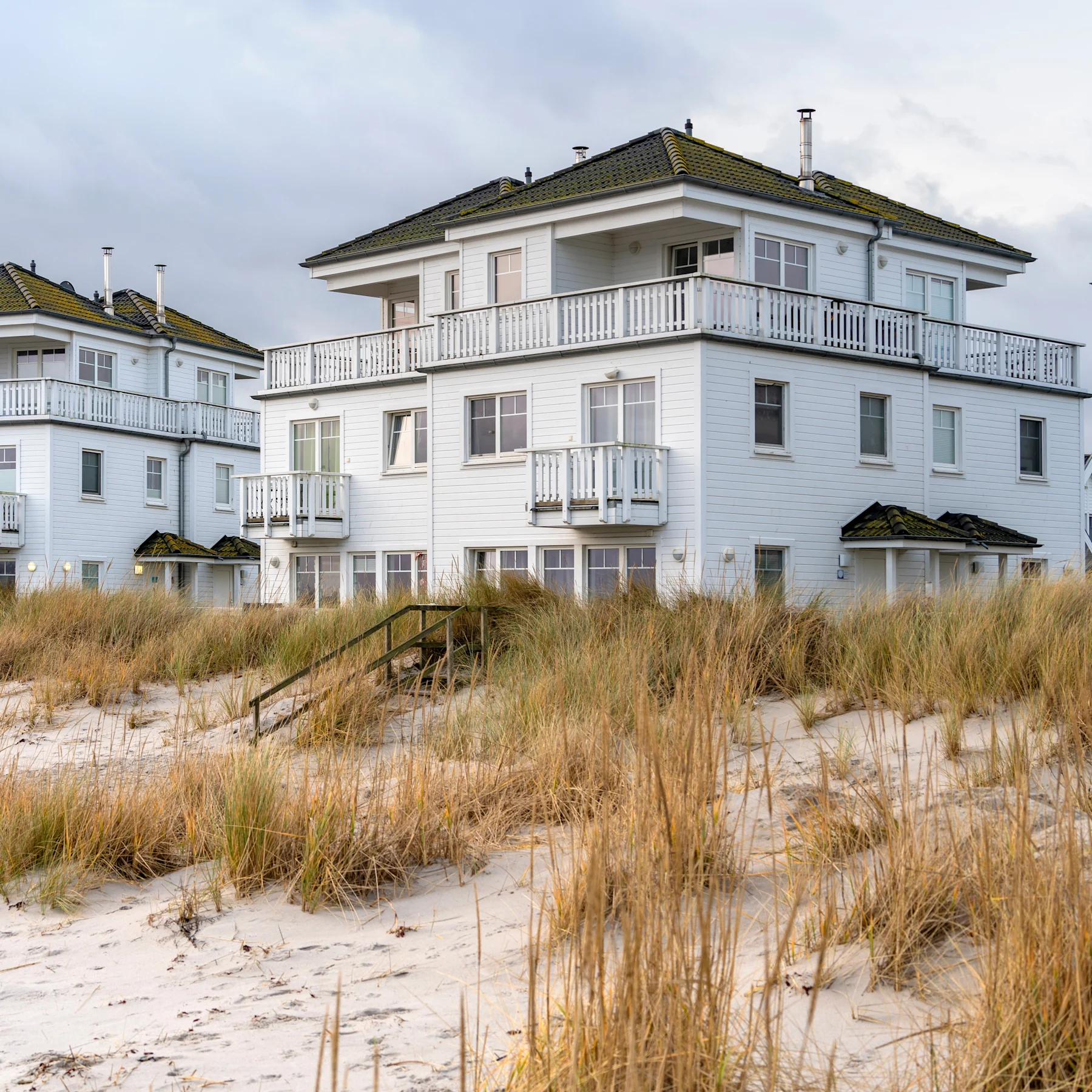 Reihe moderner, weißer Wohnhäuser mit schwarzen Dächern und Außentreppen.