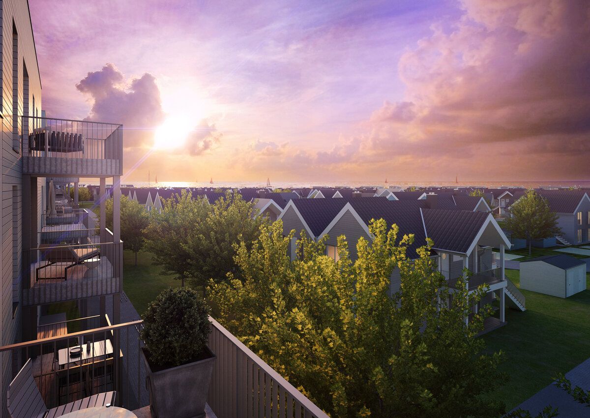 Blick von einem Balkon auf Häuser mit Gärten und Bäumen bei Sonnenuntergang.