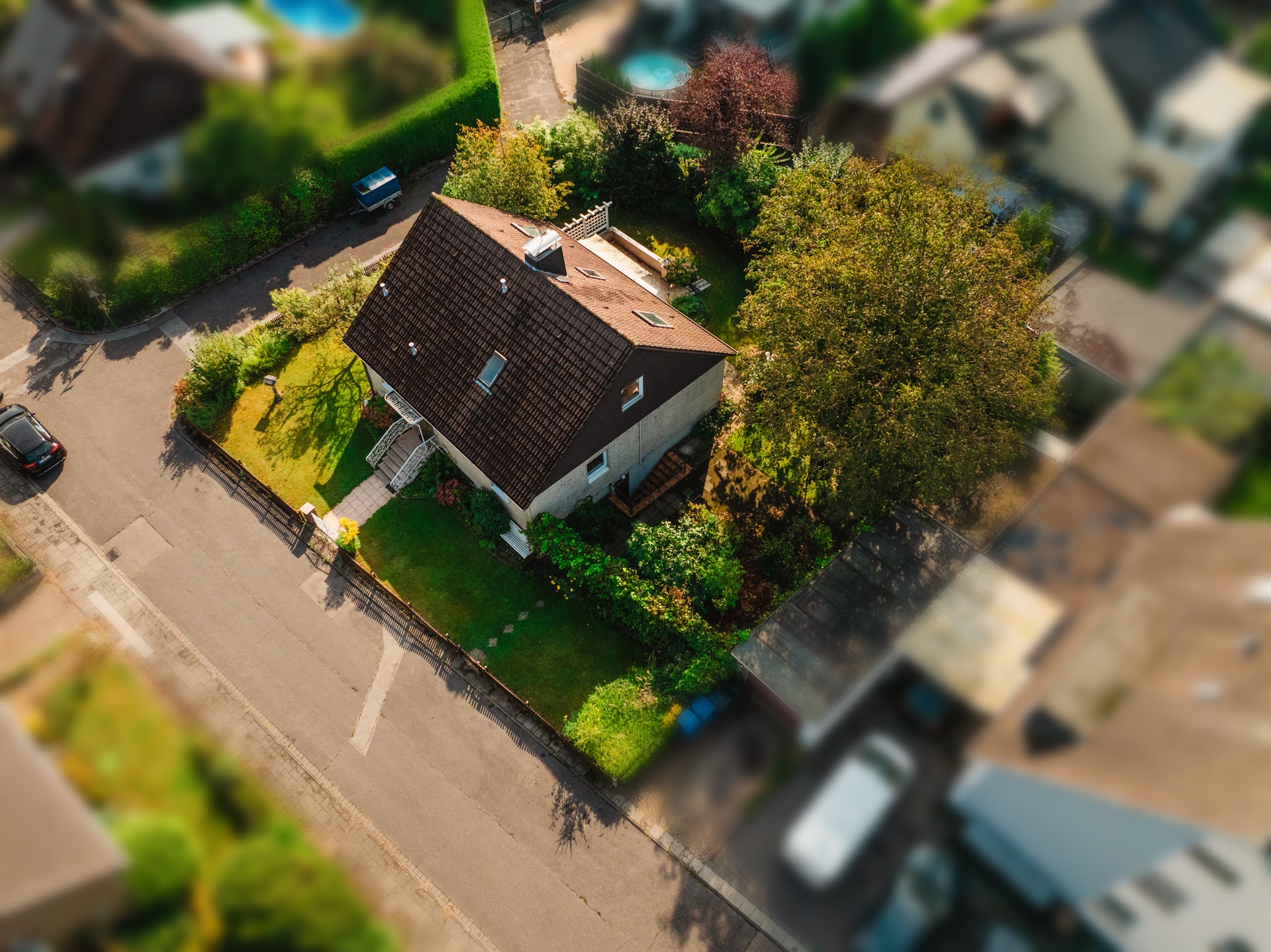 Luftaufnahme eines freistehenden Hauses mit Garten an einer Straßenecke.