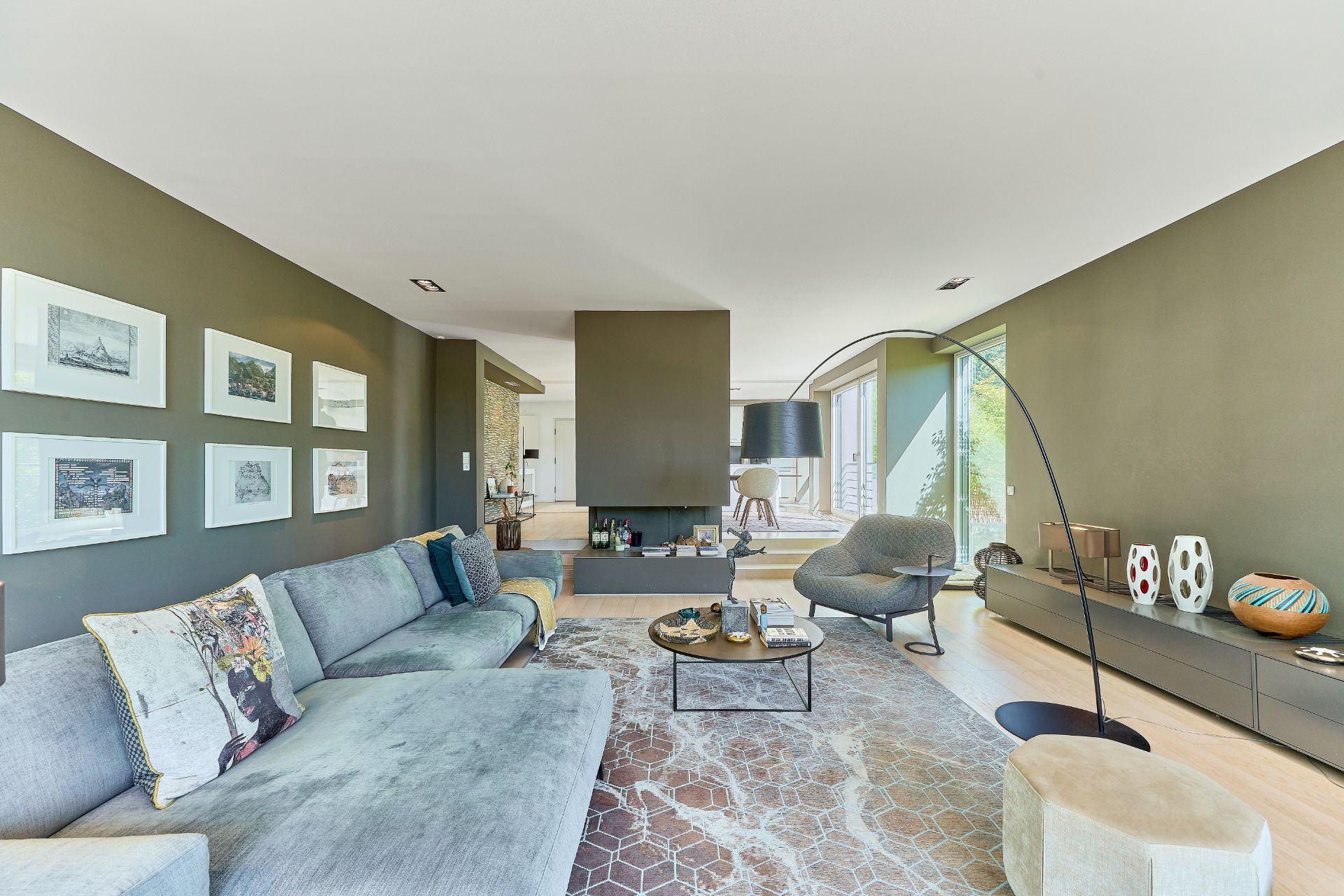 Modernes Wohnzimmer mit grauem Sofa, Couchtisch und Bildern an olivgrüner Wand.
