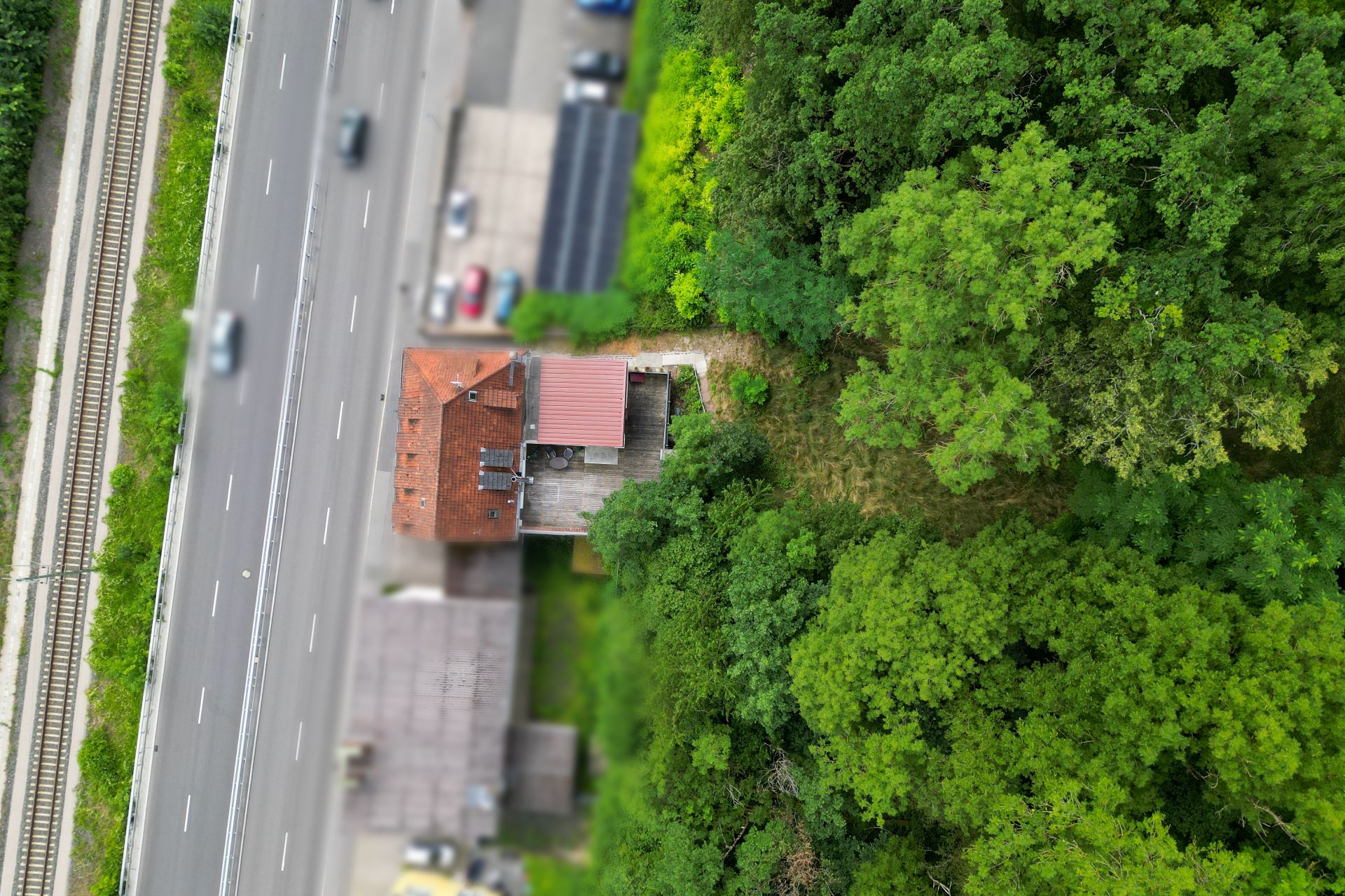 Luftaufnahme eines Wohnhauses neben einer Straße und dichtem Wald.