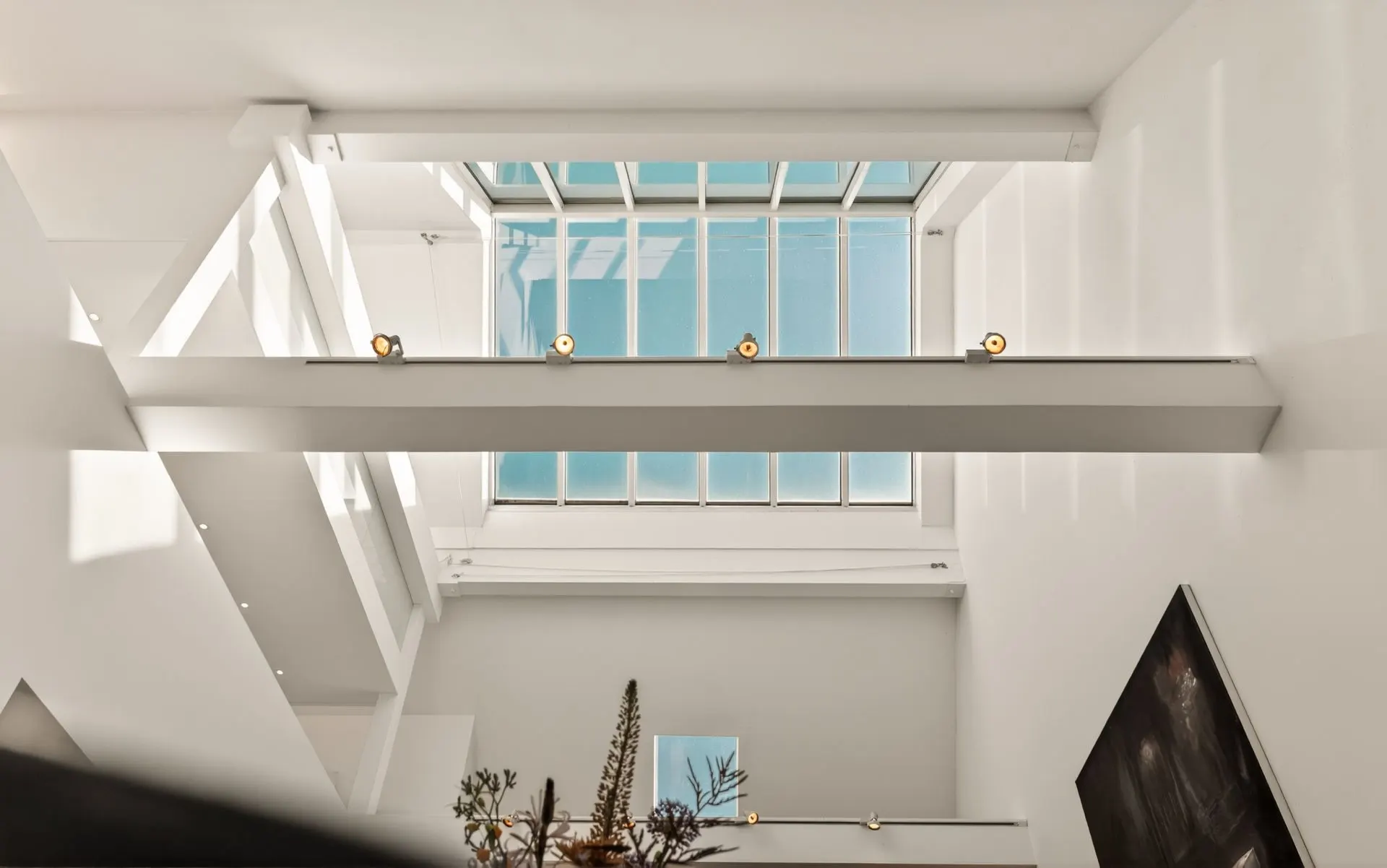 Blick nach oben auf ein großes Oberlicht und weiße Wände in einem modernen Wohnraum.