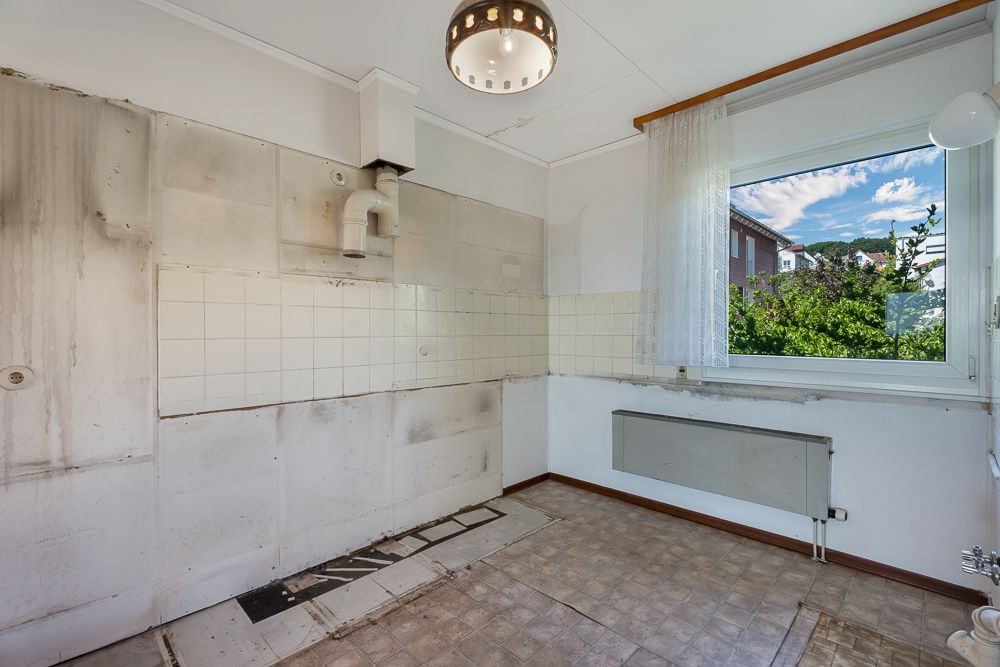 Leerer Raum mit Fliesen an der Wand, Bodenbelag, Fenster und Heizkörper.