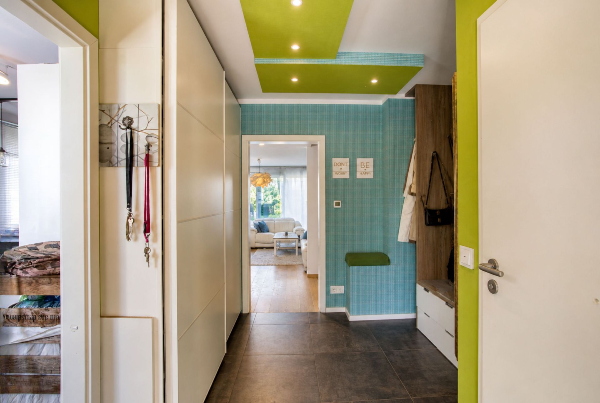 Moderner Flur mit Garderobe, Haken für Schlüssel und Blick ins helle Wohnzimmer.