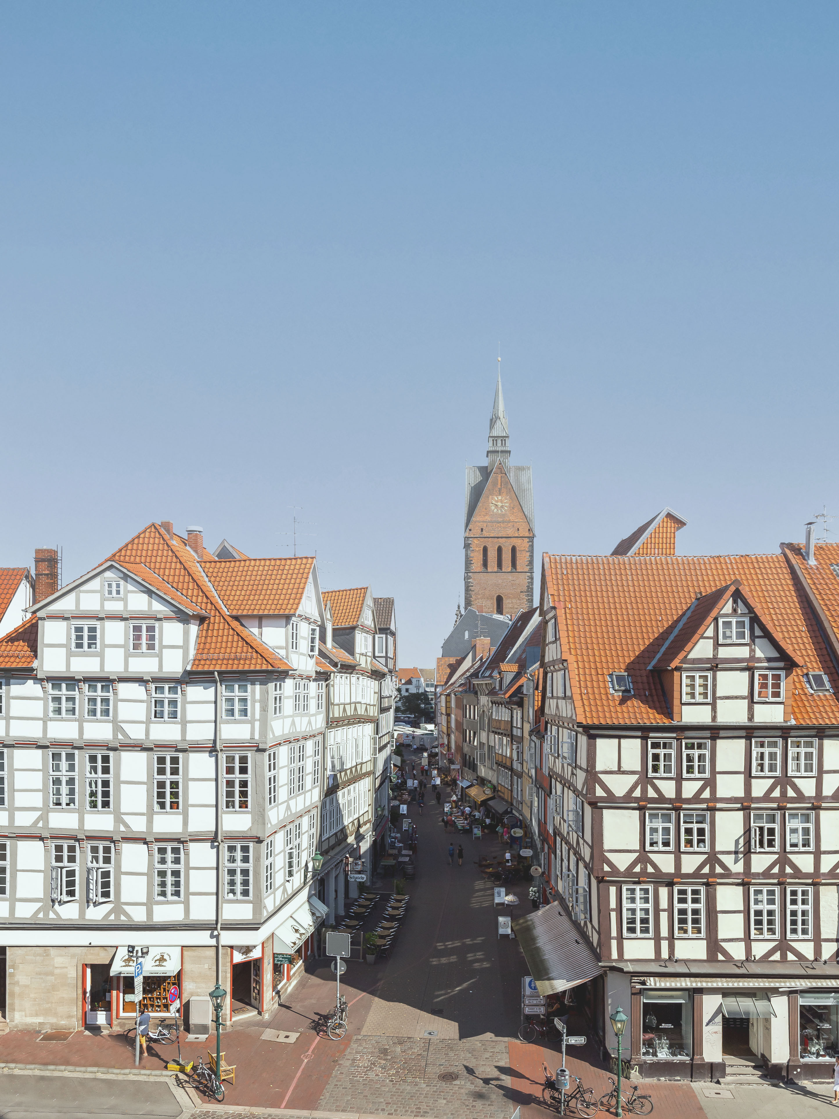 Blick auf eine Altstadtstraße mit Fachwerkhäusern und einer Kirche im Hintergrund.
