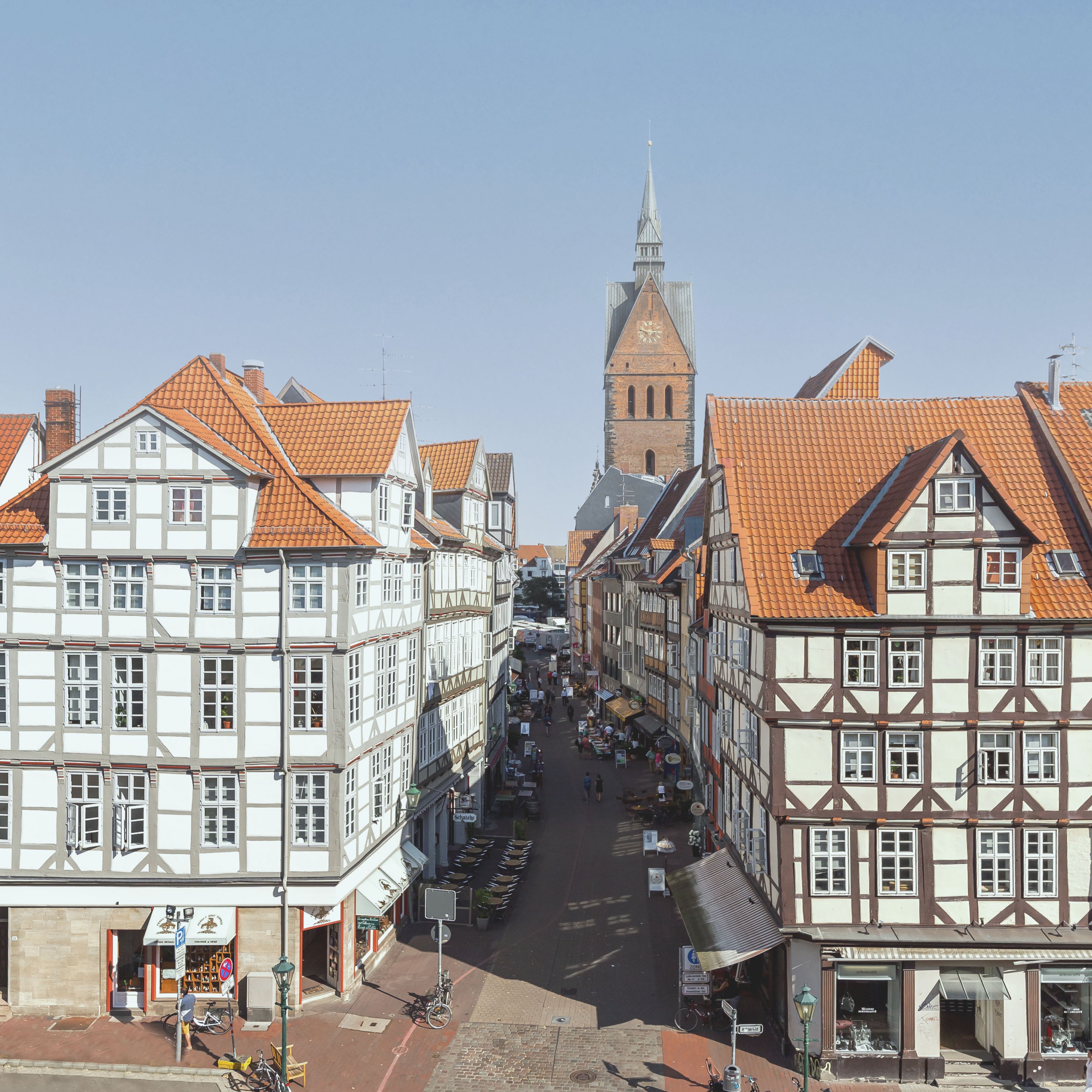 Blick auf eine Altstadtstraße mit Fachwerkhäusern und einer Kirche im Hintergrund.