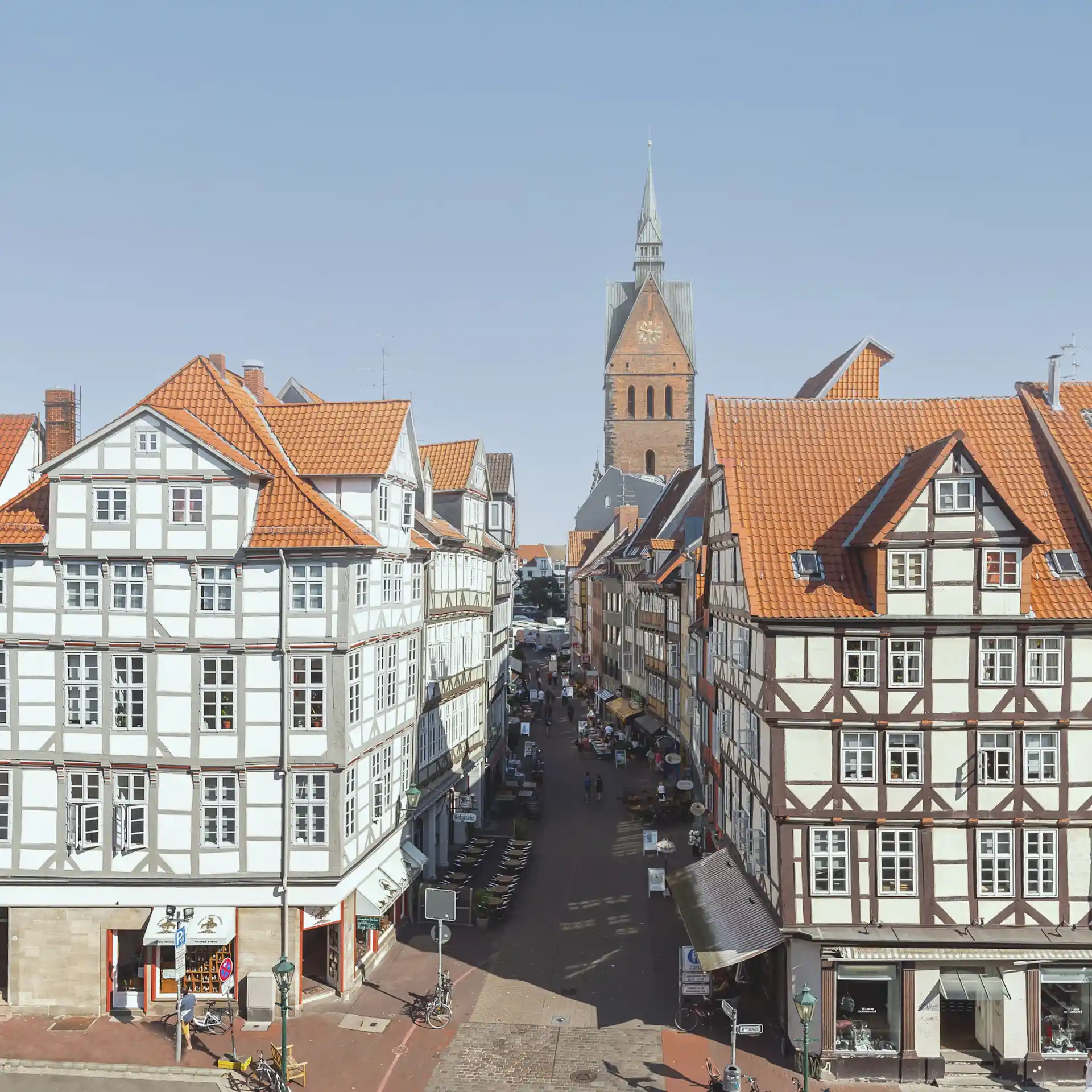 Blick auf eine Altstadtstraße mit Fachwerkhäusern und einer Kirche im Hintergrund.