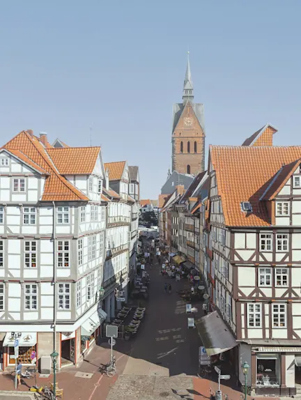 Blick auf eine Altstadtstraße mit Fachwerkhäusern und einer Kirche im Hintergrund.