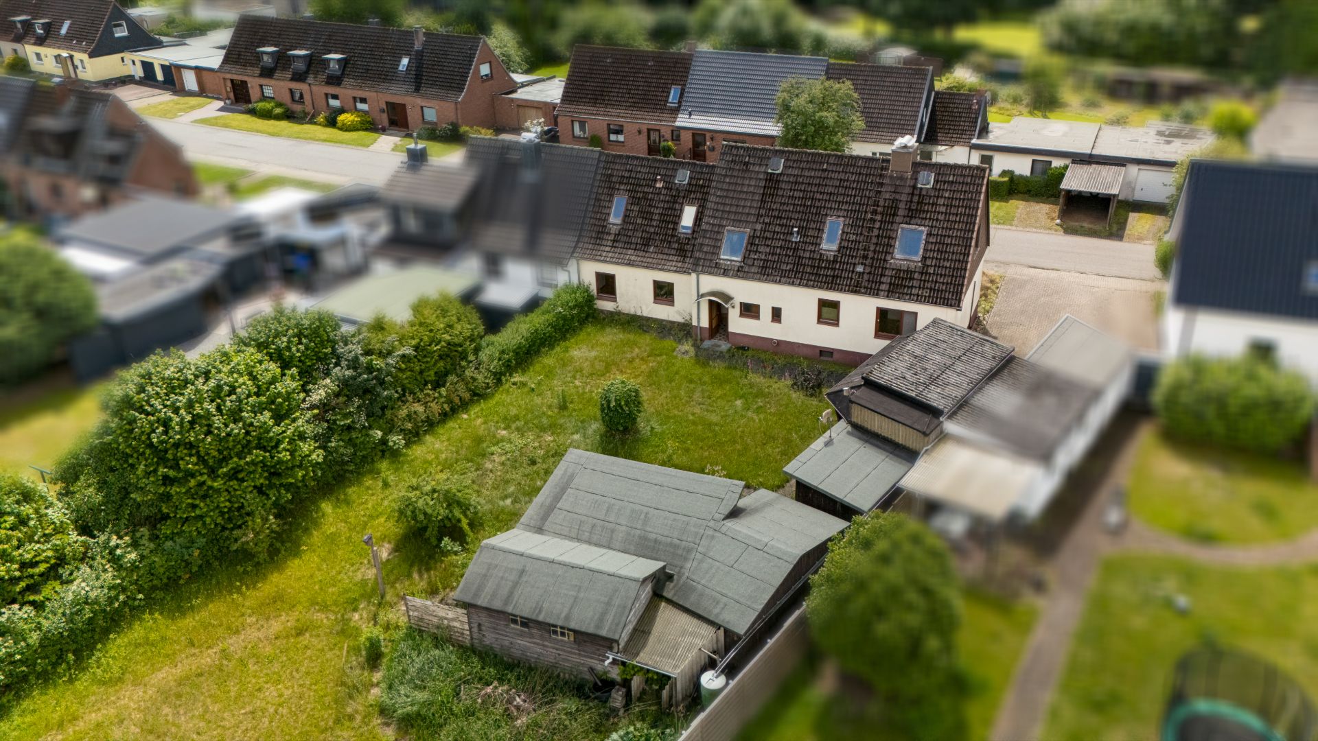 Luftaufnahme eines Wohnhauses mit angrenzendem Garten und Nebengebäuden.