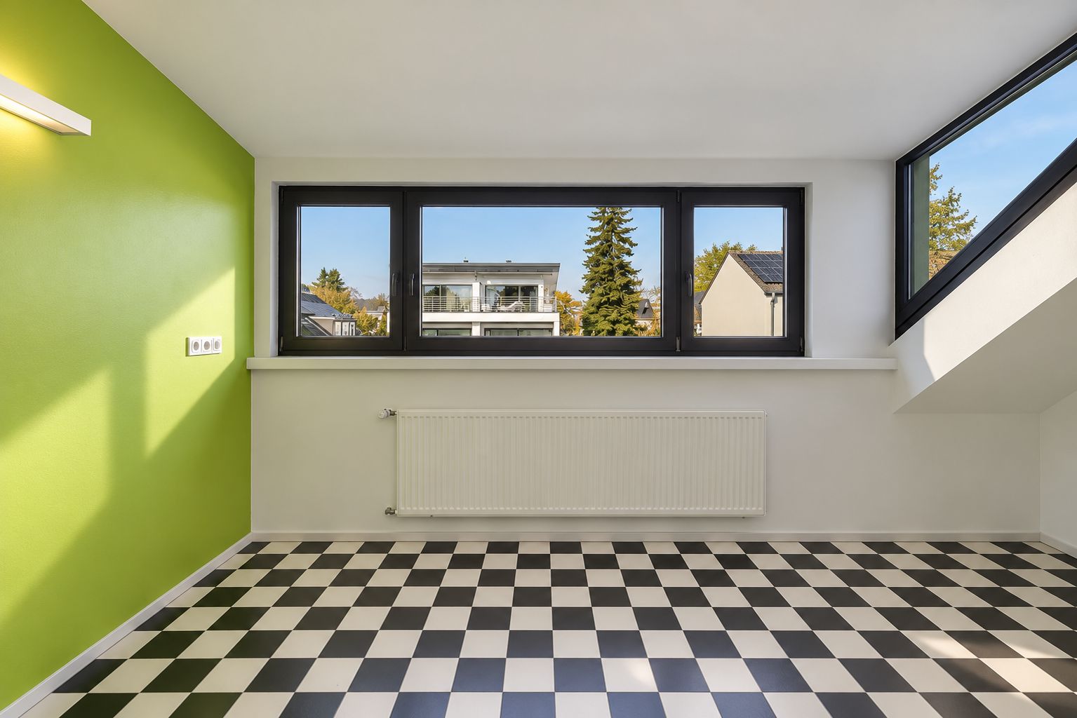 Heller Raum mit schwarz-weiß kariertem Boden, grüner Wand und großen Fenstern.