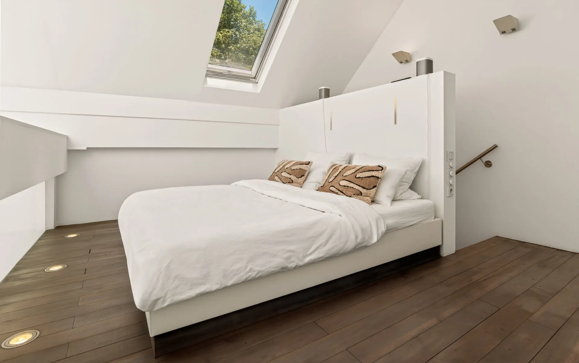 Modernes Schlafzimmer mit Doppelbett, Holzfußboden und Dachfenster, das Tageslicht hereinlässt.