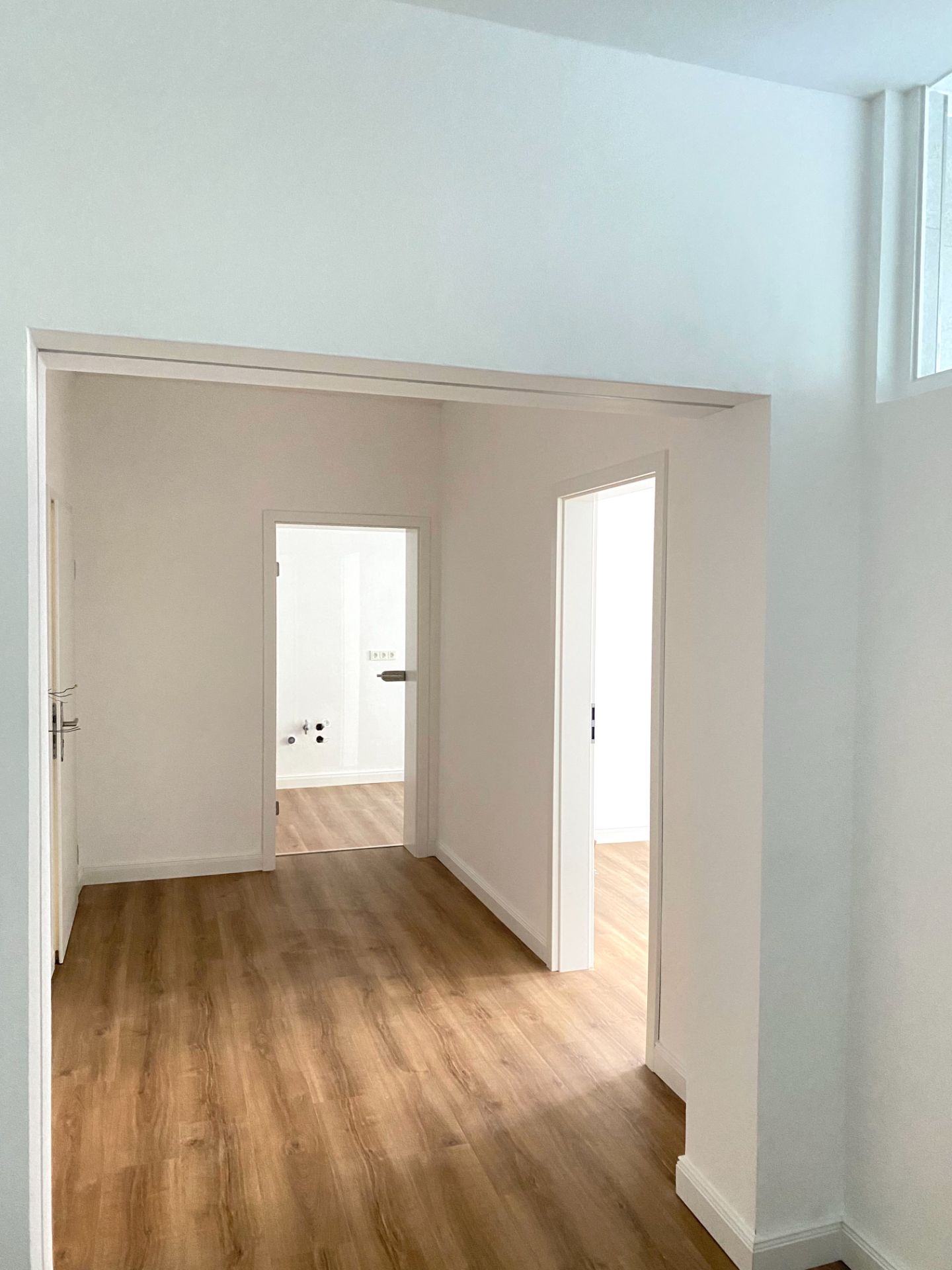 Heller Flur mit Holzboden, von dem mehrere Türen in weitere Zimmer führen.