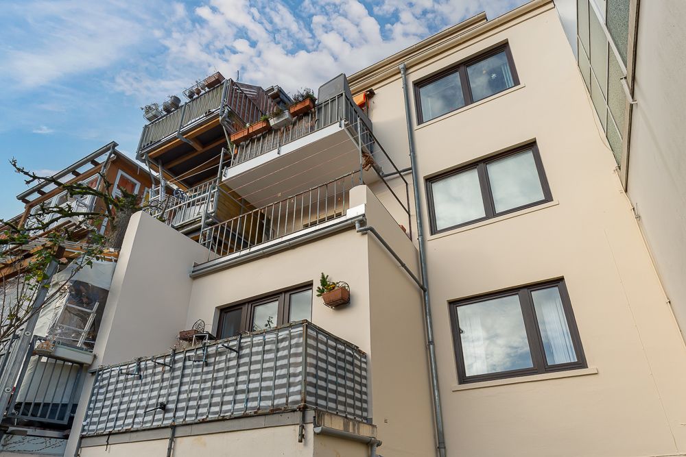 Mehrstöckiges Wohnhaus mit mehreren Balkonen und großen Fenstern, Blick von unten.