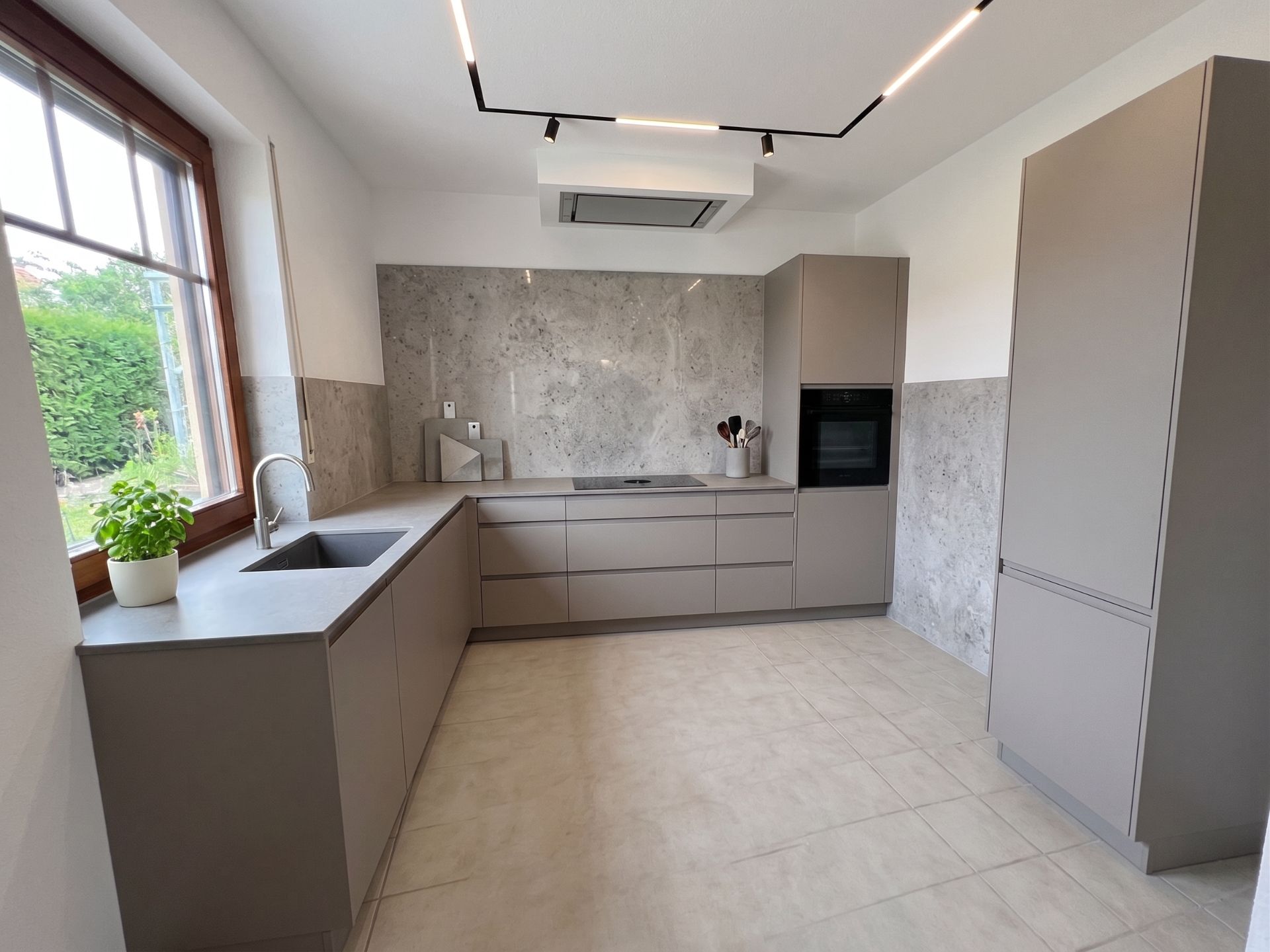 Moderne Küche mit grauen Schränken, großem Fenster und Marmor-Rückwand.