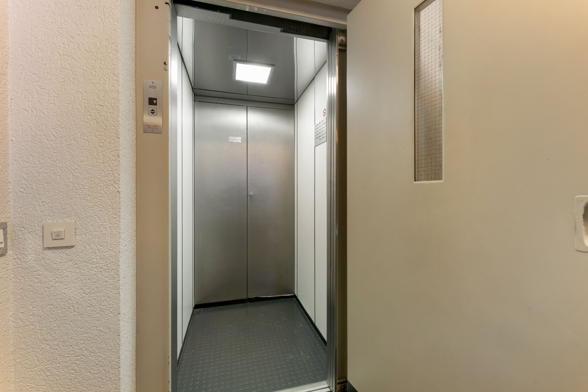 Geöffnete Aufzugtür mit Blick ins Innere eines kleinen Aufzugs in einem Wohngebäude.