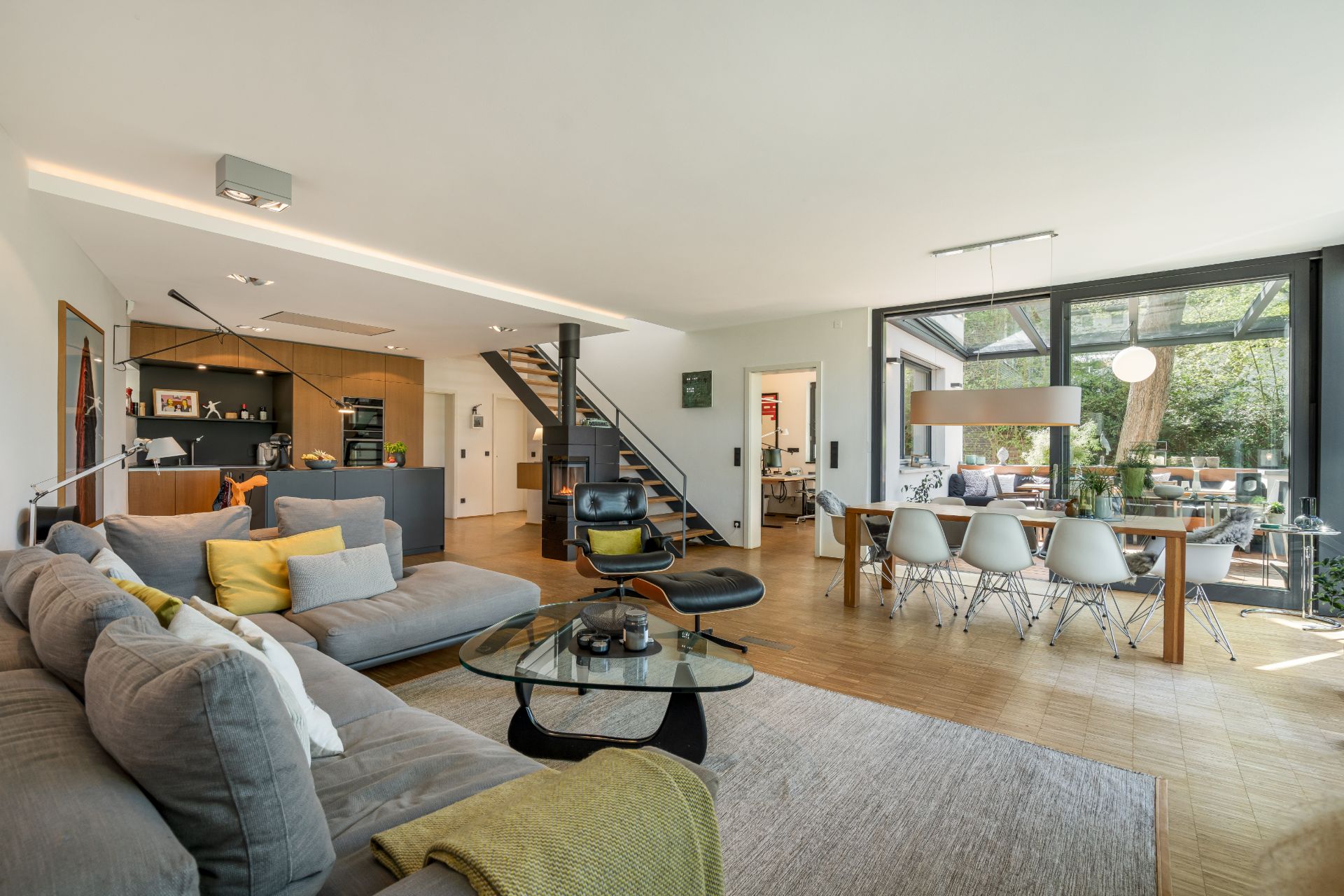 Helles Wohnzimmer mit Sofa, Esstisch, moderner Küche und Zugang zur Terrasse.