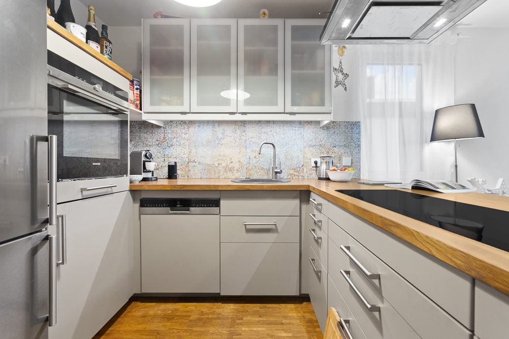 Moderne Einbauküche mit Holzarbeitsplatte, Herd, Spüle und Hängeschränken.