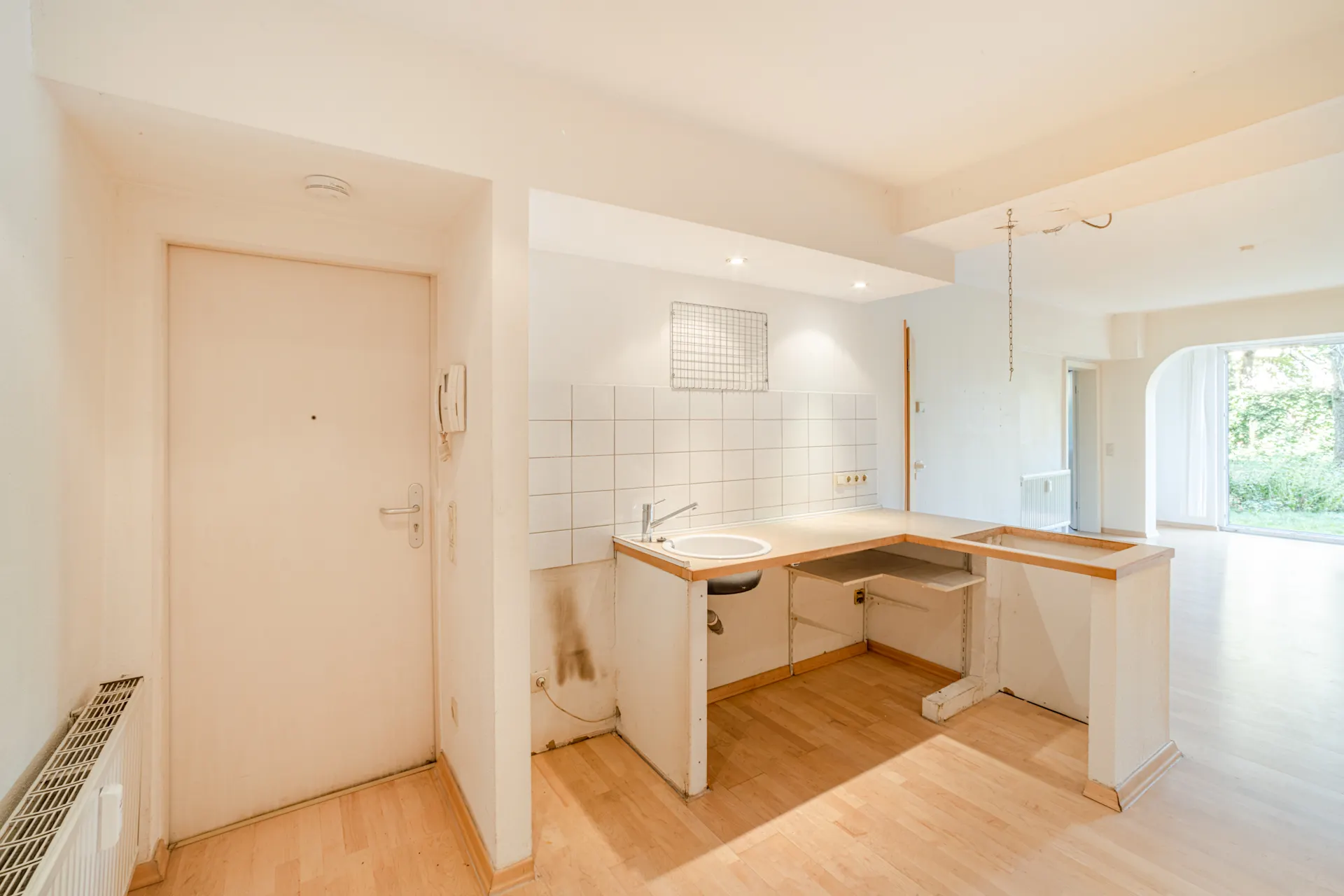 Helle Wohnung mit kleinem Küchenbereich, Spüle und offenem Grundriss, Blick ins Grüne.