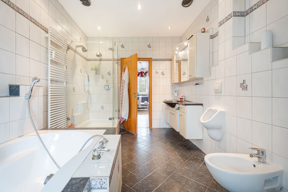 Modernes Badezimmer mit Badewanne, Dusche, Bidet, Urinal und großem Waschbeckenbereich.