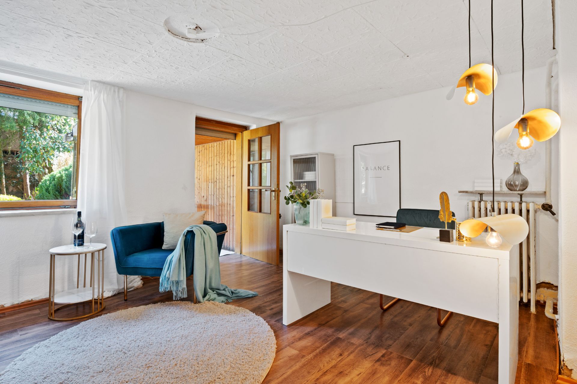 Modernes Arbeitszimmer mit weißem Schreibtisch, Sessel, Teppich und großen Fenstern.