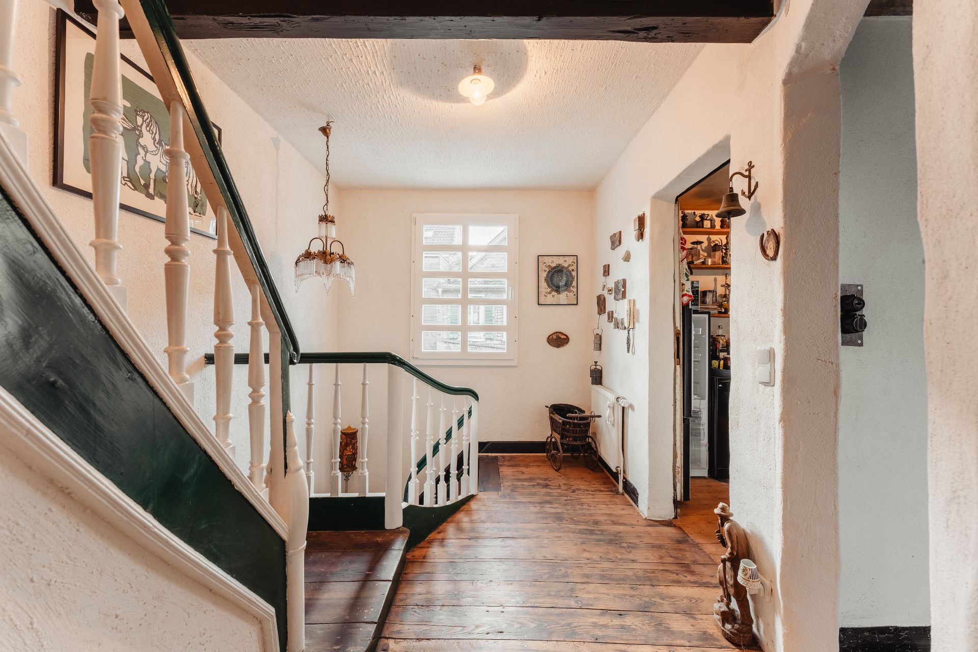Heller Flur mit Holztreppe, Holzfußboden und Fenster, Bilder und Dekoration an den Wänden.
