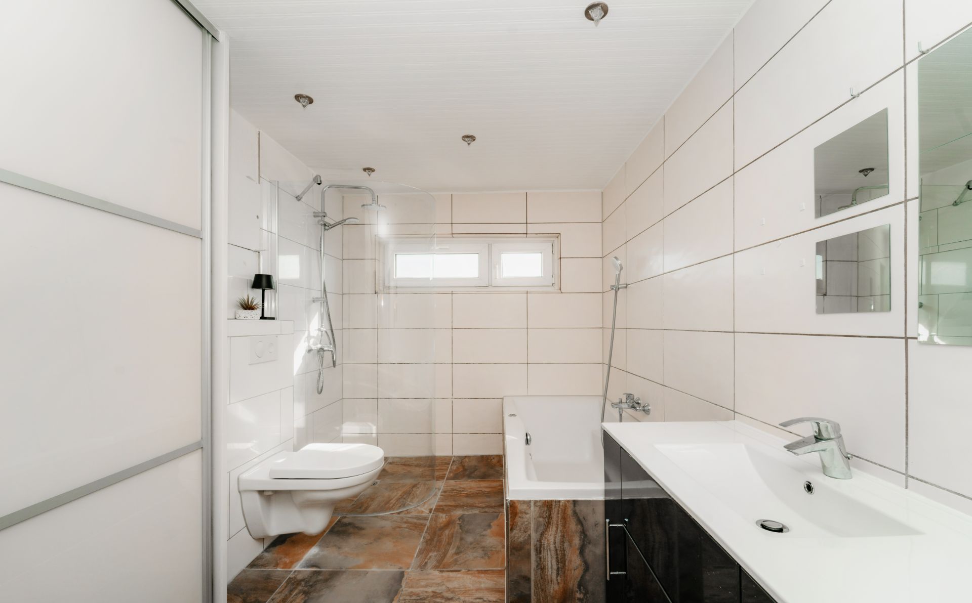 Modernes Badezimmer mit Dusche, Badewanne, WC, Waschbecken und weiß gefliesten Wänden.