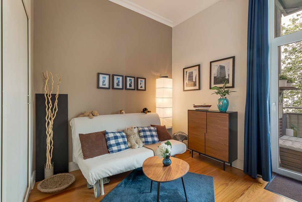 Helles Wohnzimmer mit Sofa, Couchtisch, Teppich, Stehlampe und Balkonzugang.