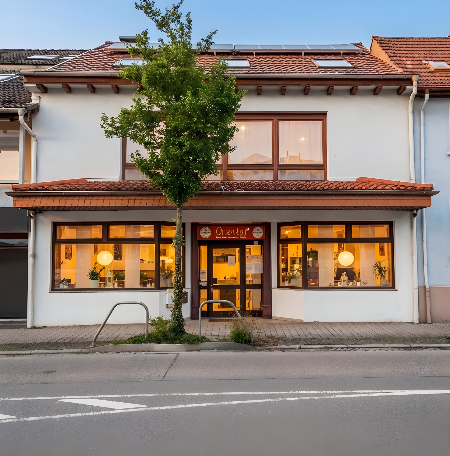 Zweistöckiges Wohnhaus mit großen Fenstern, Baum vor dem Eingang.
