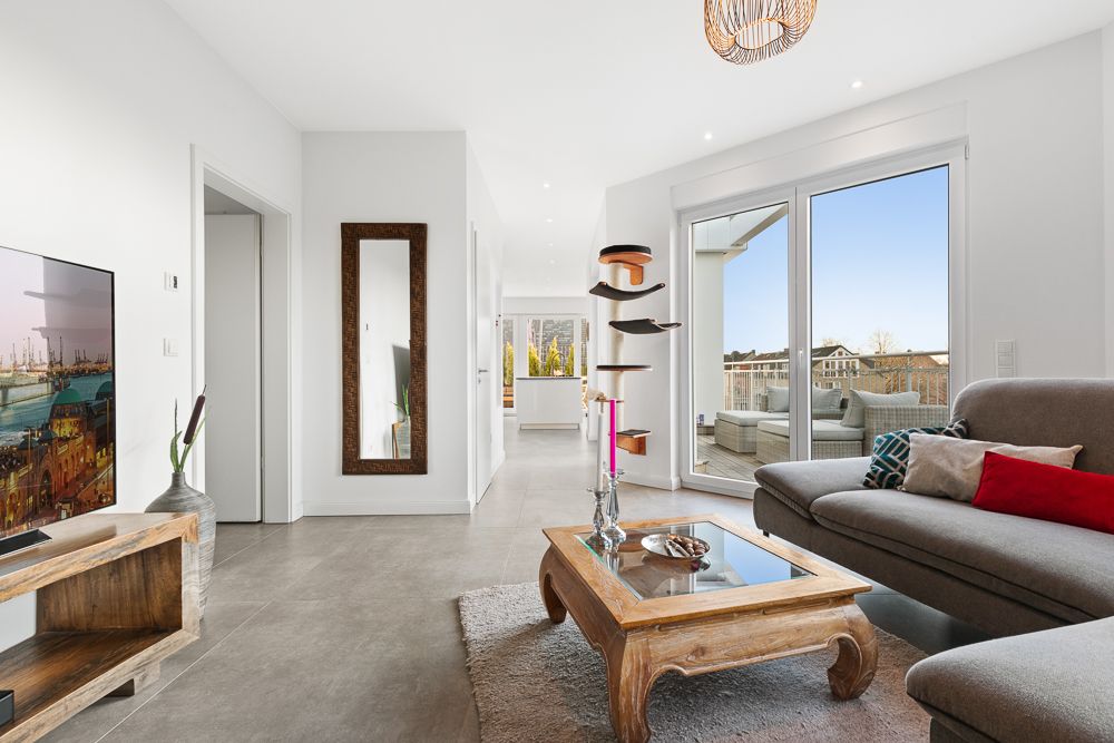 Modernes Wohnzimmer mit Sofa, Couchtisch, großem Spiegel und Zugang zu einer Terrasse.