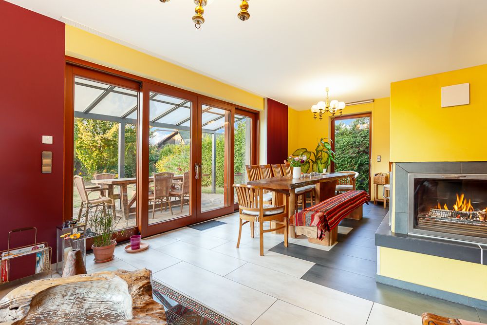 Heller Essbereich mit Holztisch, Stühlen, Kamin und Zugang zur Terrasse mit Gartenblick.