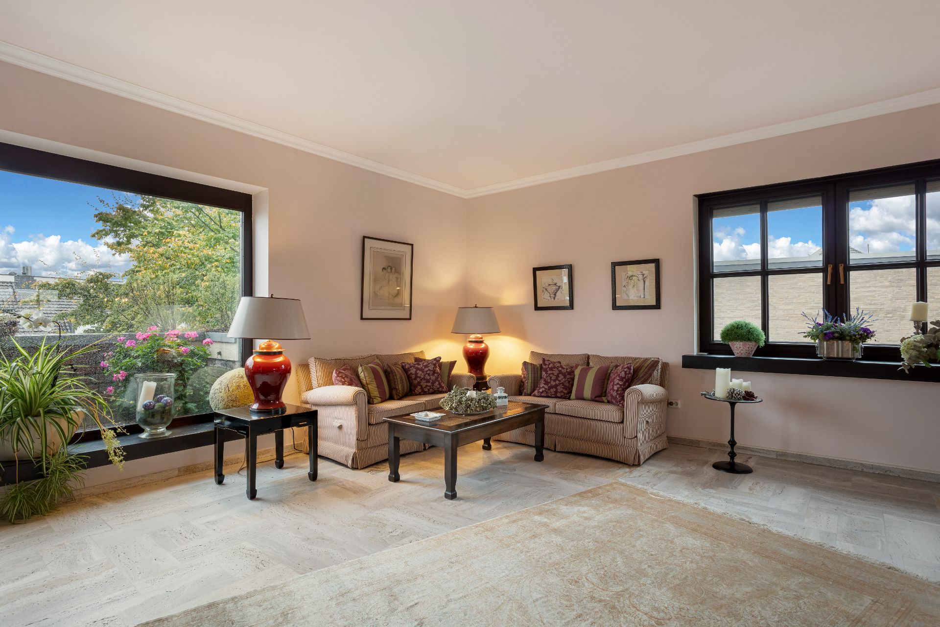 Helles Wohnzimmer mit zwei Sofas, Couchtisch, Lampen, großen Fenstern und Pflanzen.