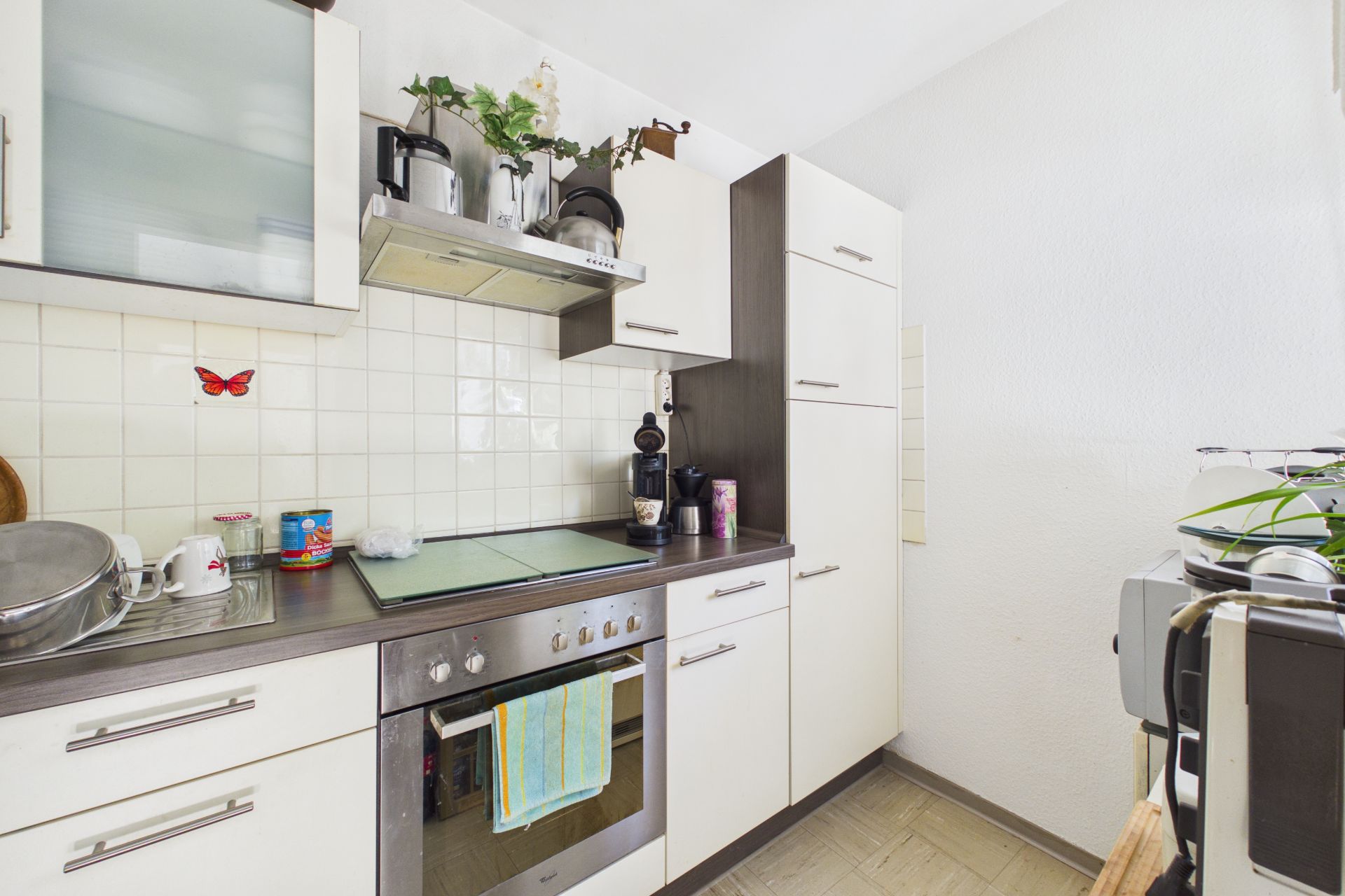 Helle, kompakte Küche mit weißen Schränken, Herd, Backofen und Fliesenspiegel.