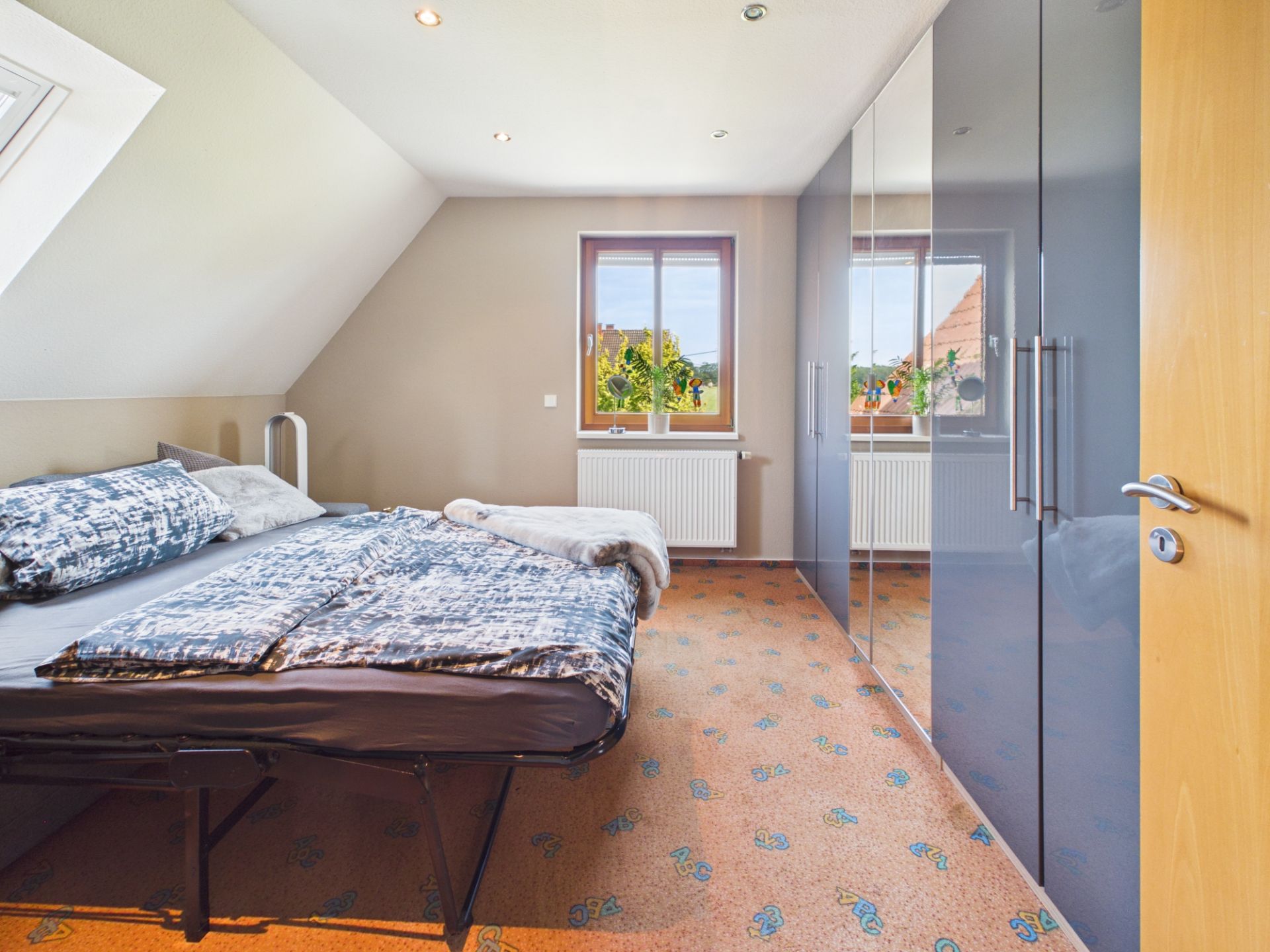 Schlafzimmer mit Doppelbett, großem Kleiderschrank und Fenster mit Ausblick.