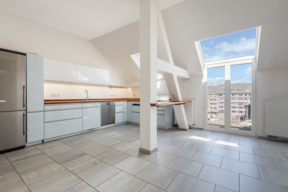 Helle, moderne Einbauküche mit großem Fenster und Blick auf Wohngebäude.