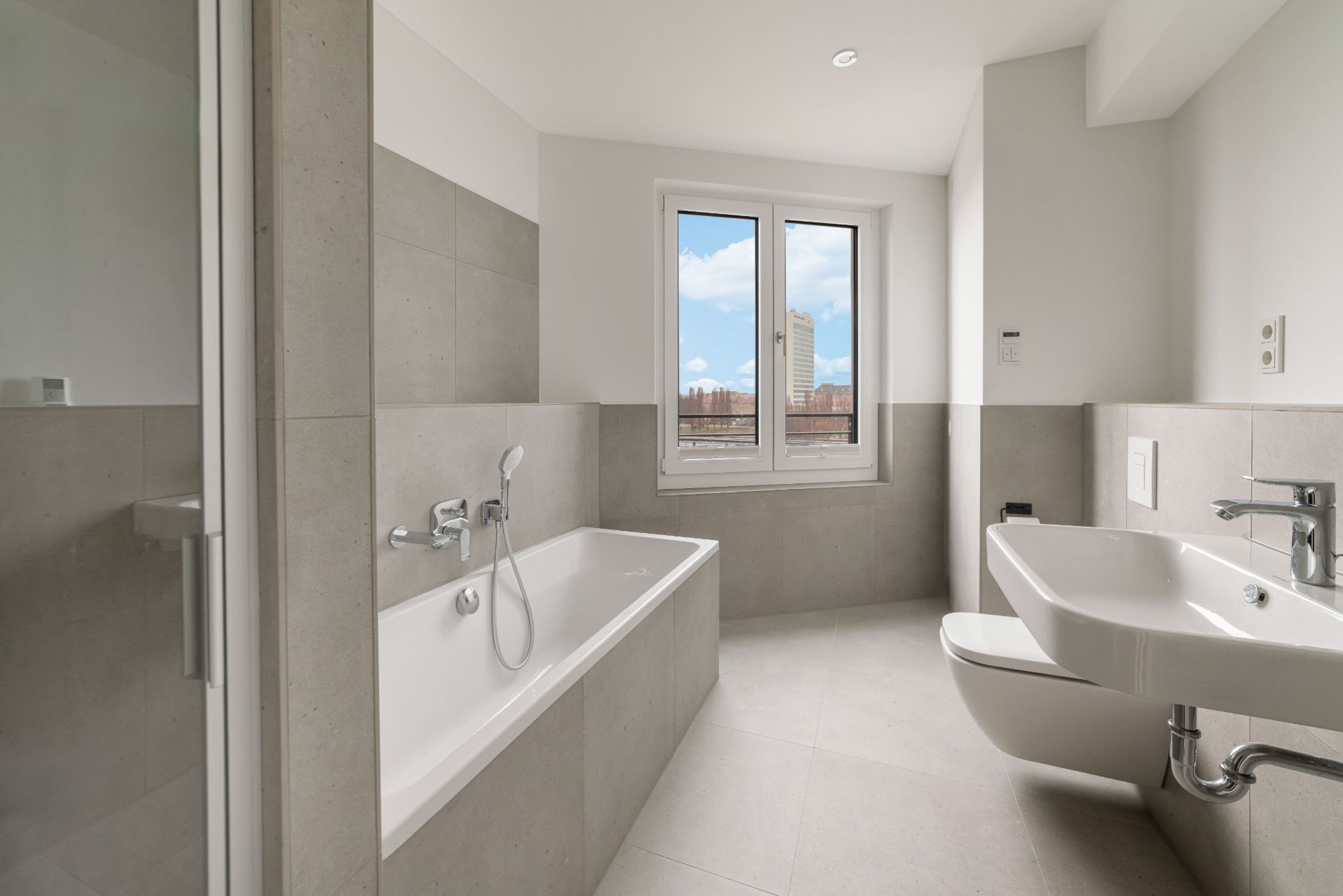 Modernes Badezimmer mit Badewanne, Dusche, WC, Waschbecken und Fenster.