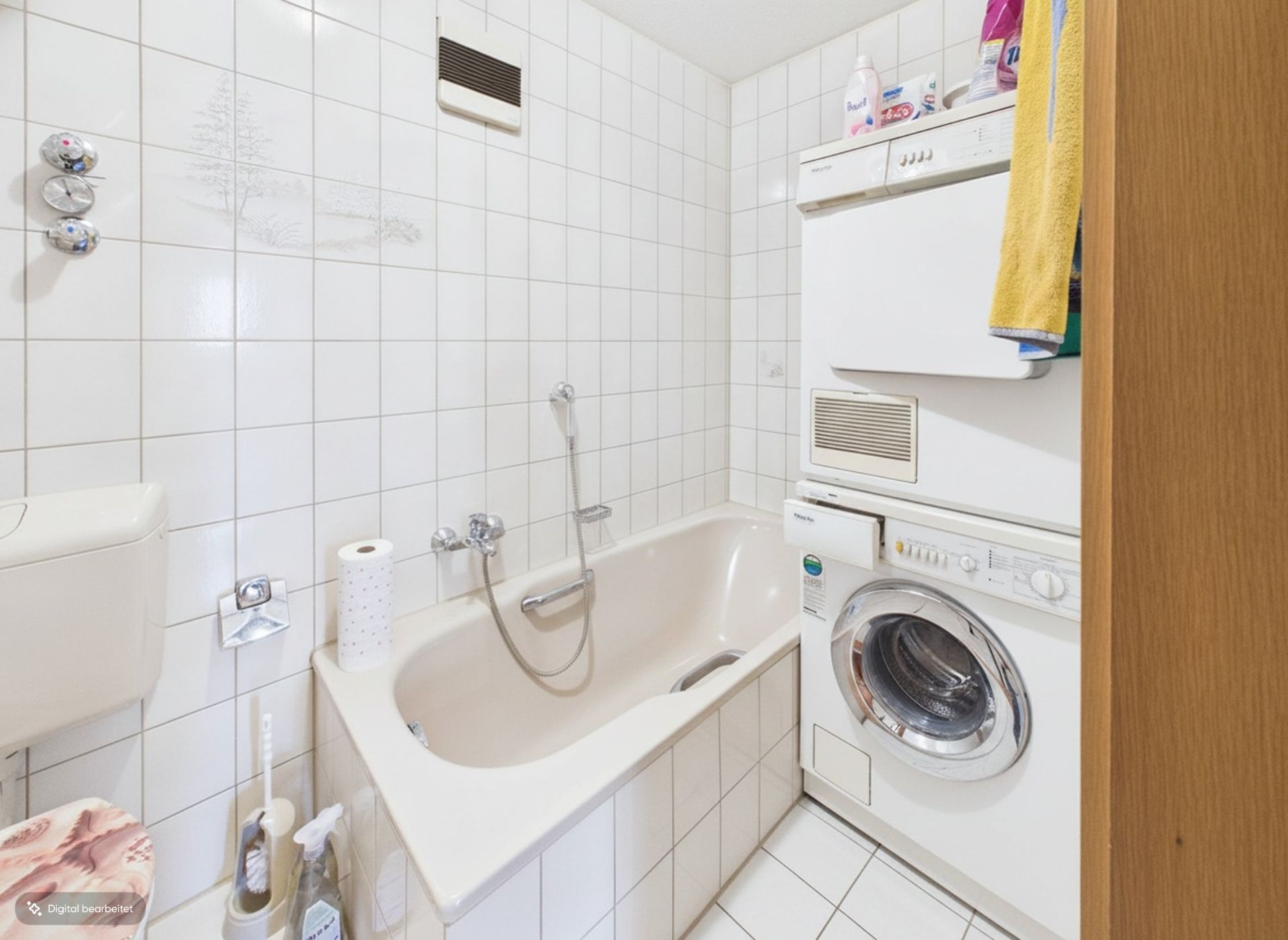 Kleines Badezimmer mit Badewanne, Waschmaschine und Trockner, weiße Fliesen an den Wänden.