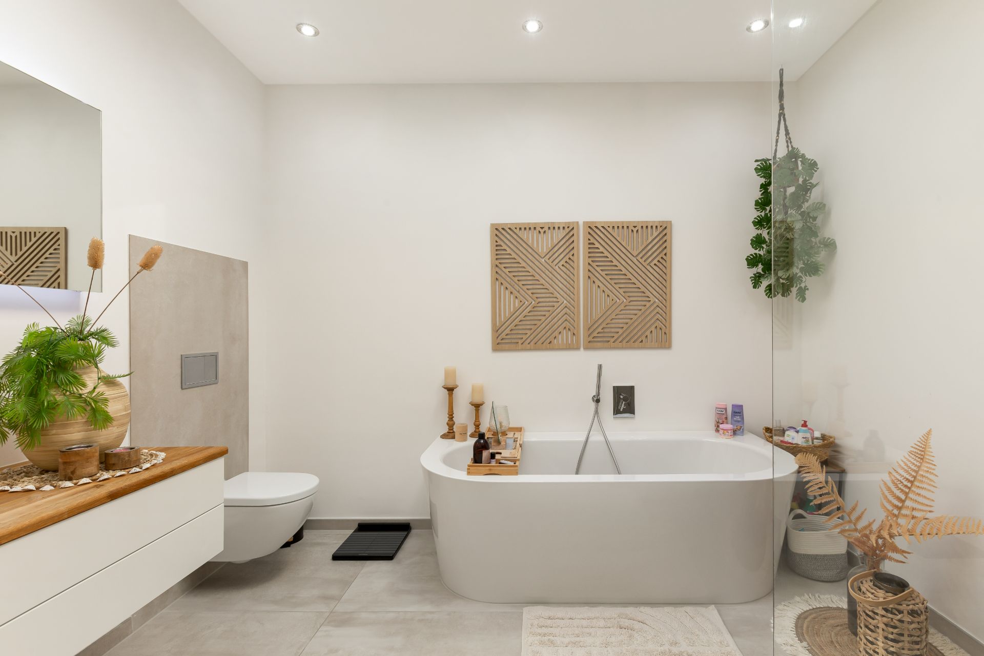 Modernes Badezimmer mit freistehender Badewanne, Toilette und dekorativen Pflanzen.