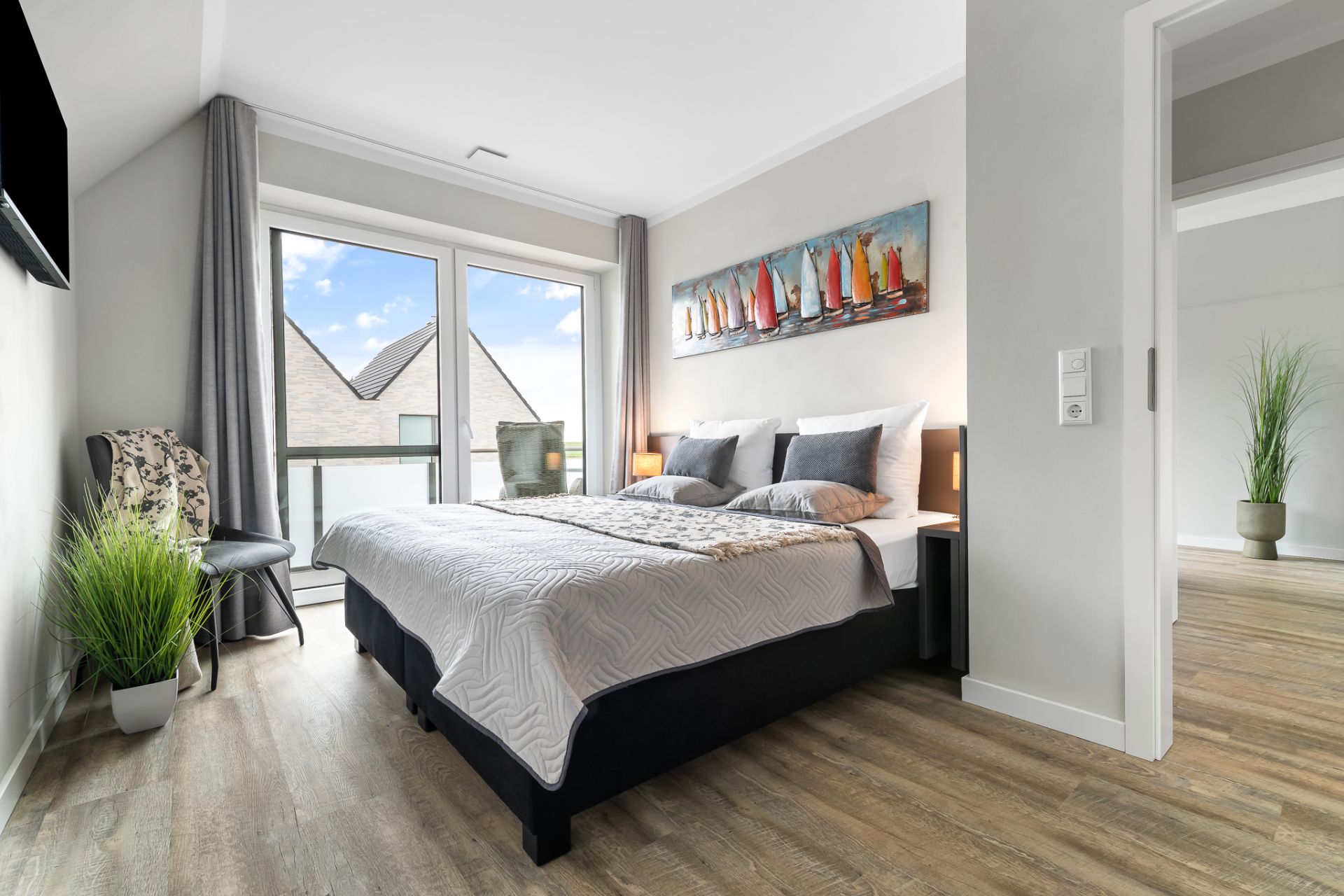 Modernes Schlafzimmer mit Doppelbett, großen Fenstern und dekorativem Gemälde über dem Bett.