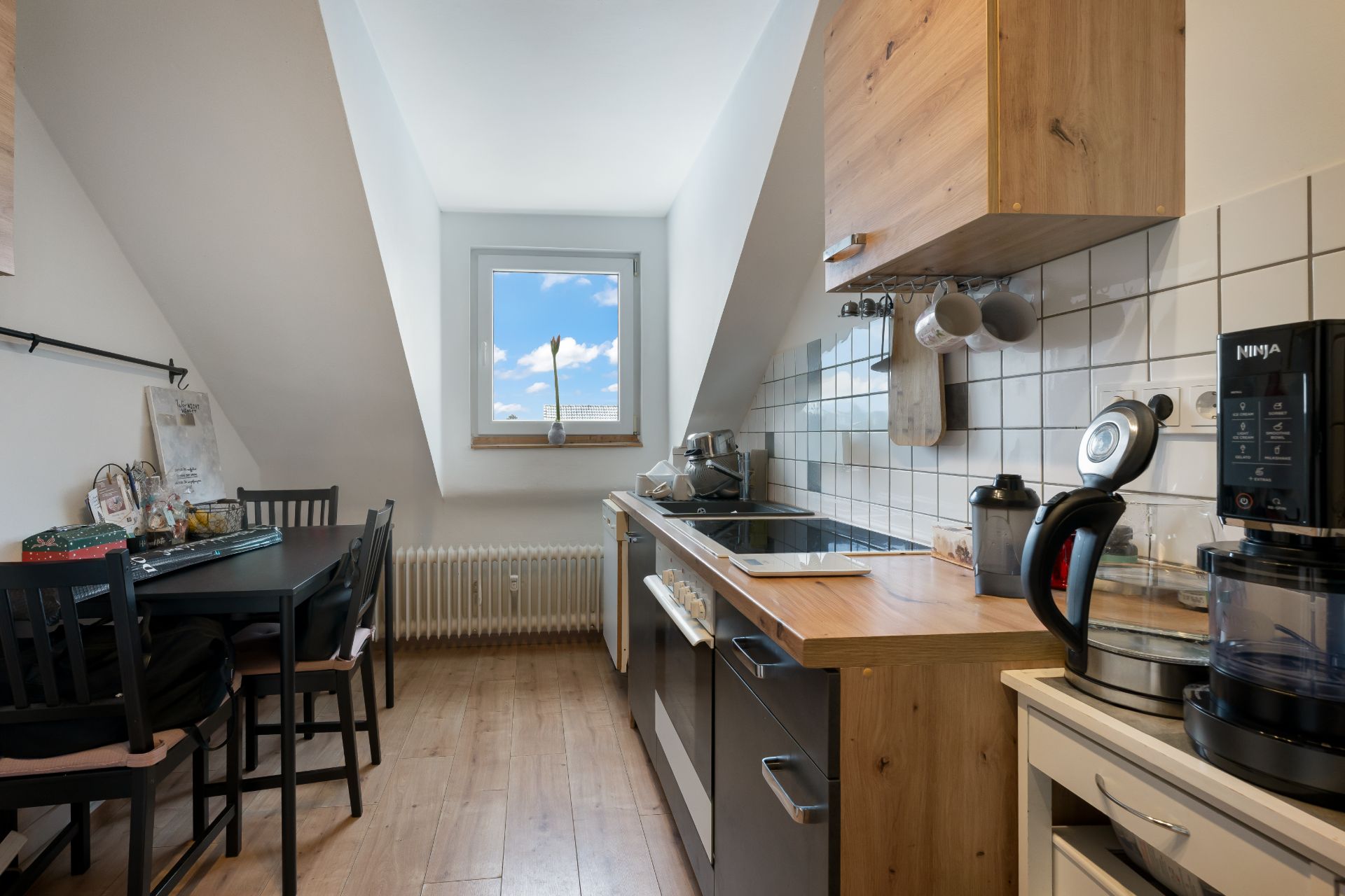 Moderne Küche mit Esstisch, Holzfußboden und Fenster mit Blick auf den Himmel.
